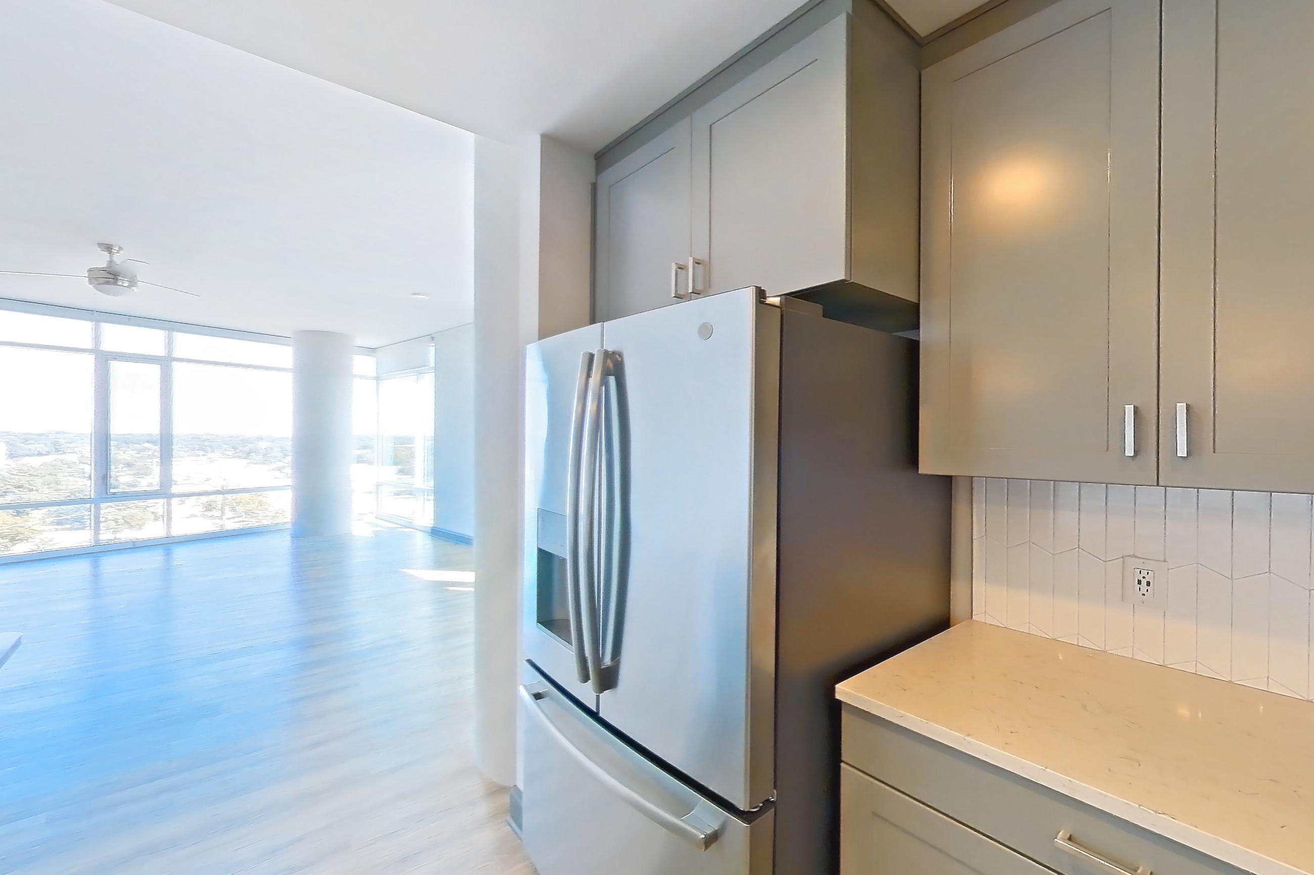 Kitchen with dishwasher, electric range, light countertops, light stone countertops, light wood-finish flooring, microwave, oven/range, refrigerator, stainless steel appliances, water & ice dispenser, and white appliances, Apartment 1032 at Cortland Glenwood South