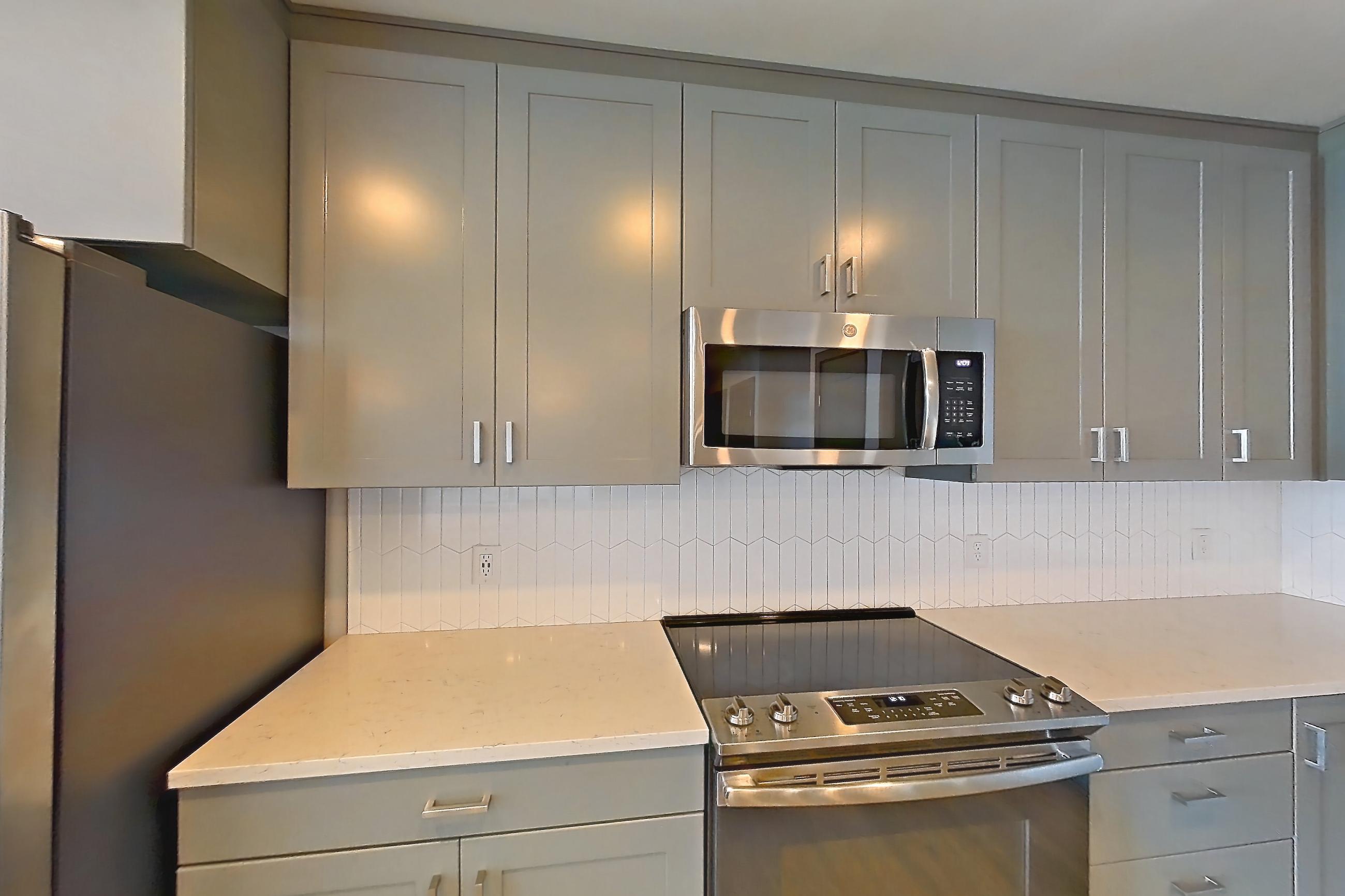 Kitchen with dishwasher, electric range, light countertops, light stone countertops, light wood-finish flooring, microwave, oven/range, refrigerator, stainless steel appliances, water & ice dispenser, and white appliances, Apartment 1032 at Cortland Glenwood South