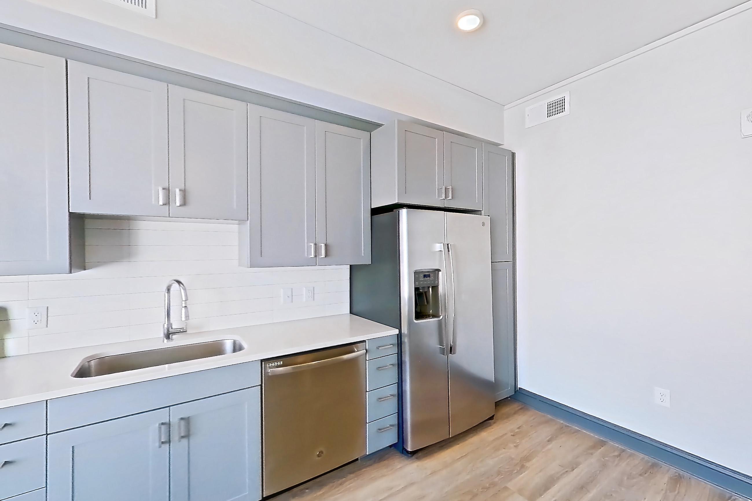 Living room with dishwasher, electric range, light countertops, light stone countertops, light wood-finish flooring, microwave, oven/range, refrigerator, stainless steel appliances, and water & ice dispenser, Apartment 1037 at Cortland Glenwood South