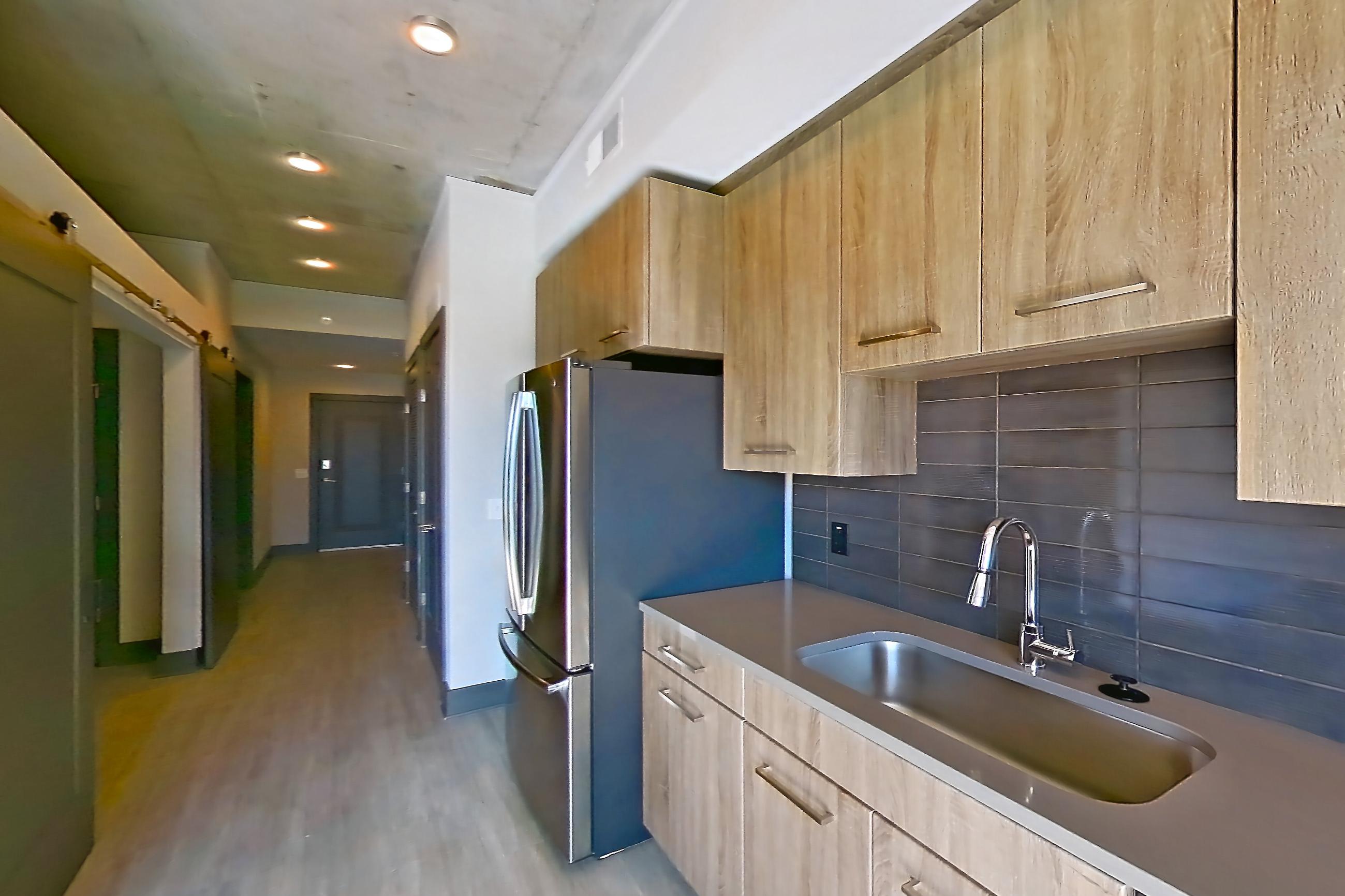 Kitchen with dark countertops, dishwasher, electric range, light wood-finish flooring, oven/range, refrigerator, and stainless steel appliances, Apartment 1105 at Cortland Glenwood South