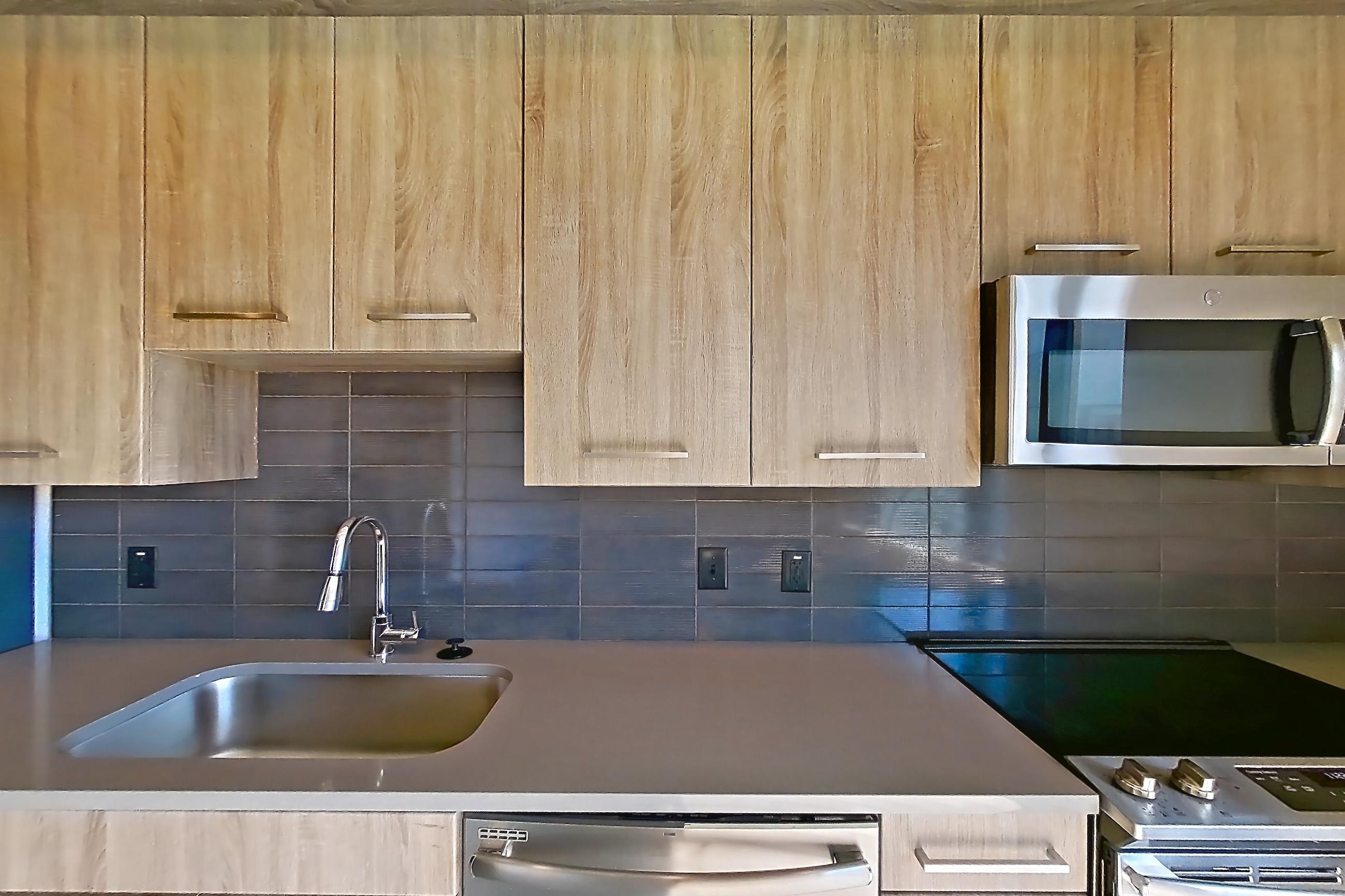 Kitchen with dark countertops, dishwasher, electric range, light wood-finish flooring, oven/range, refrigerator, and stainless steel appliances, Apartment 1105 at Cortland Glenwood South