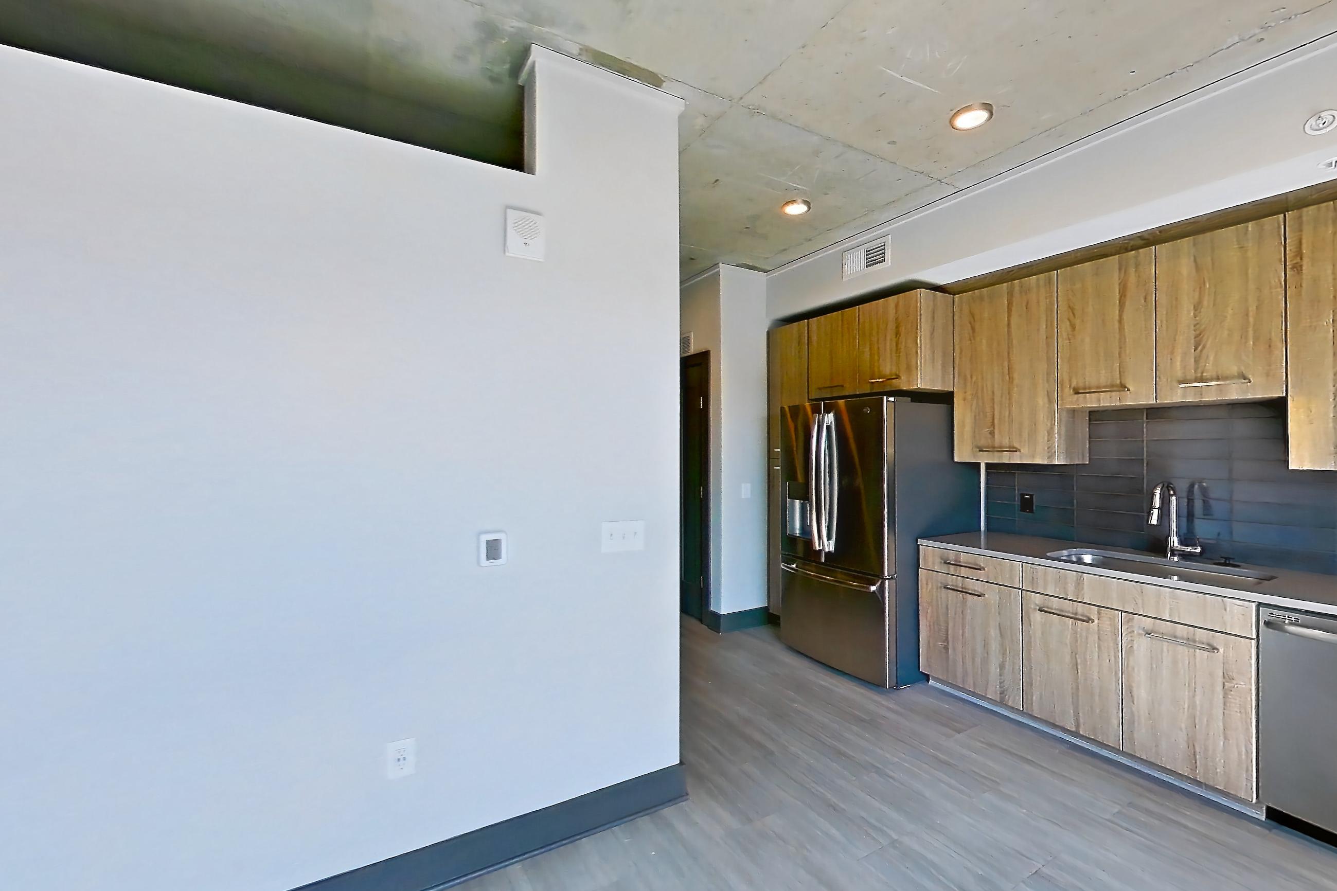 Living room with dark wood-finish flooring, refrigerator, and stainless steel appliances, Apartment 1105 at Cortland Glenwood South