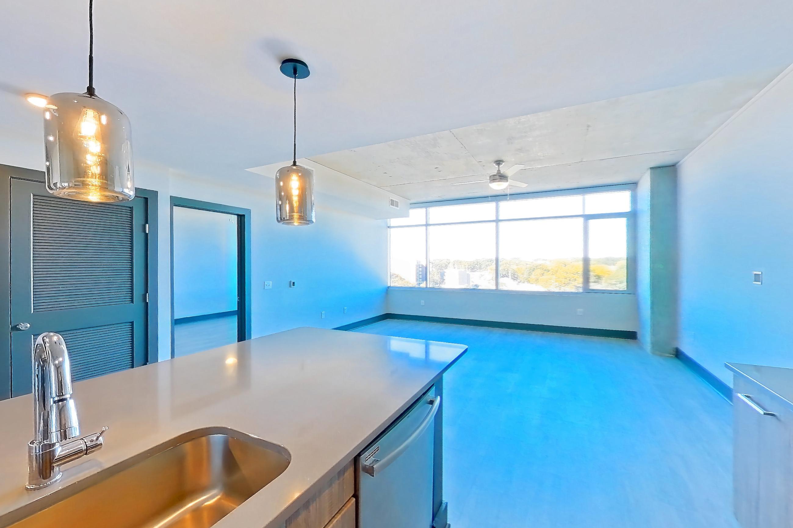 Kitchen with dark countertops, dishwasher, electric range, light countertops, light stone countertops, light wood-finish flooring, microwave, oven/range, refrigerator, stainless steel appliances, and water & ice dispenser, Apartment 1108 at Cortland Glenwood South