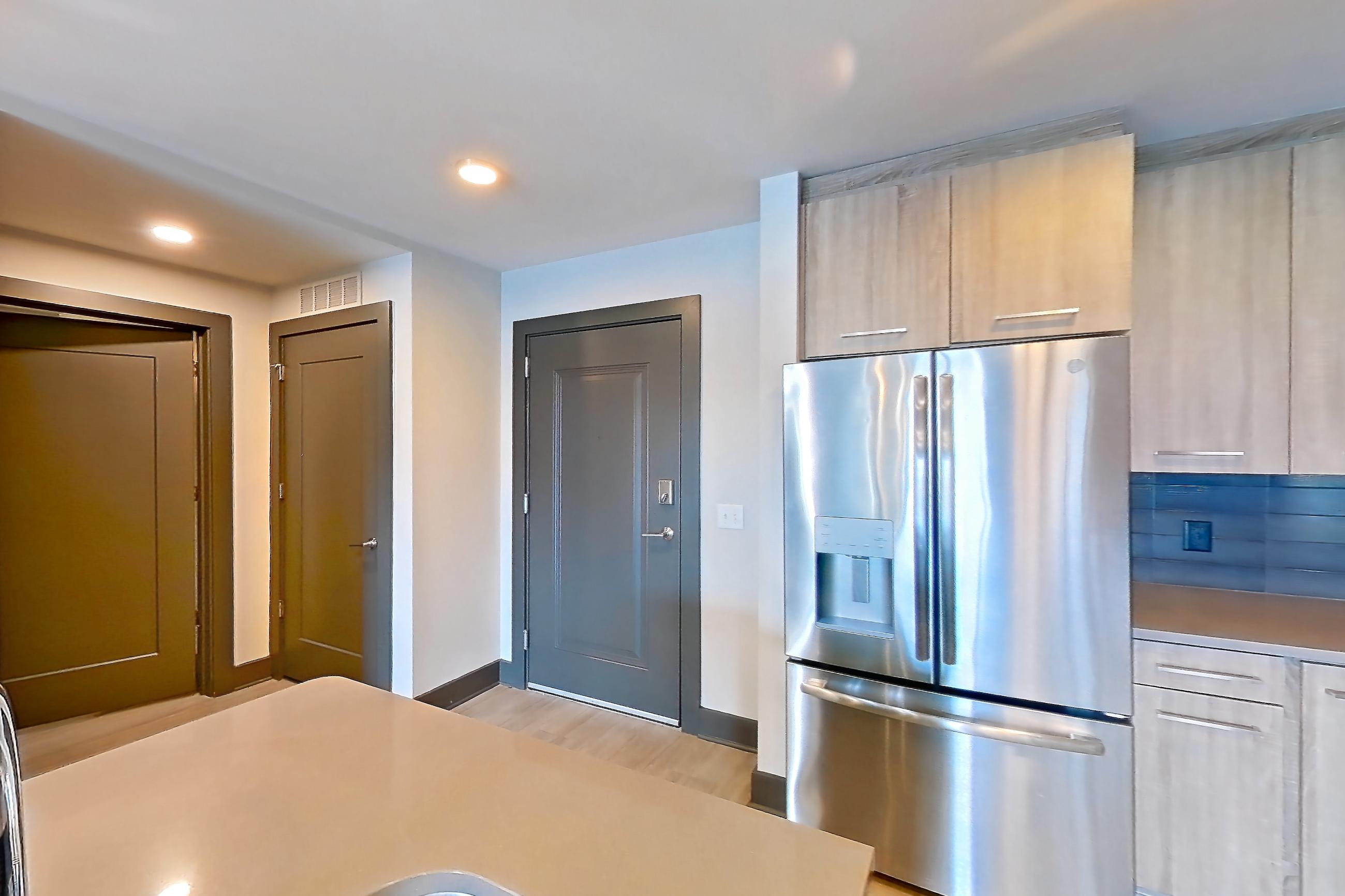 Kitchen with electric range, light countertops, light wood-finish flooring, microwave, oven/range, refrigerator, stainless steel appliances, and water & ice dispenser, Apartment 1113 at Cortland Glenwood South