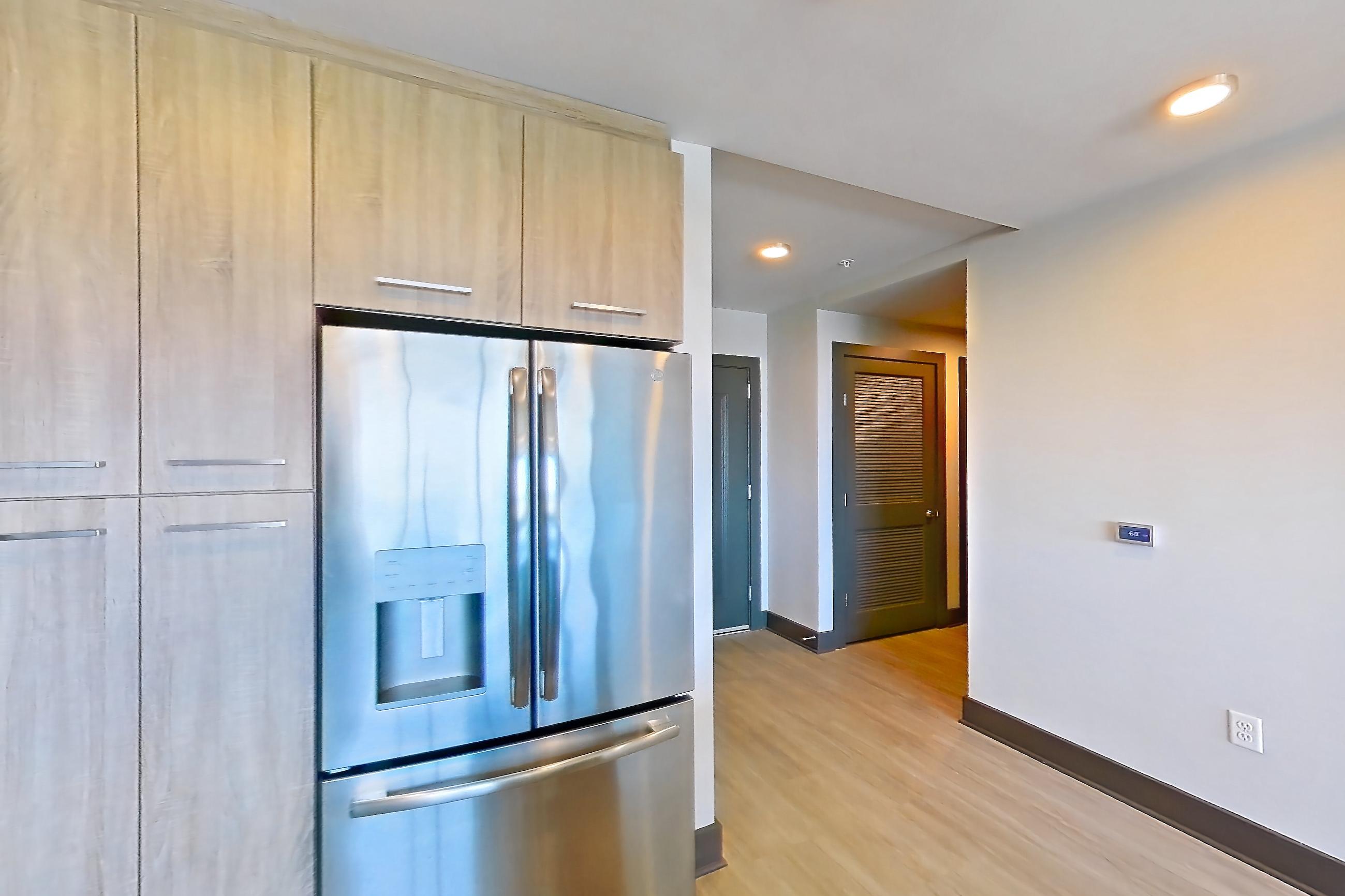 Kitchen with dark countertops, electric range, light countertops, light wood-finish flooring, microwave, oven/range, refrigerator, stainless steel appliances, and water & ice dispenser, Apartment 1116 at Cortland Glenwood South