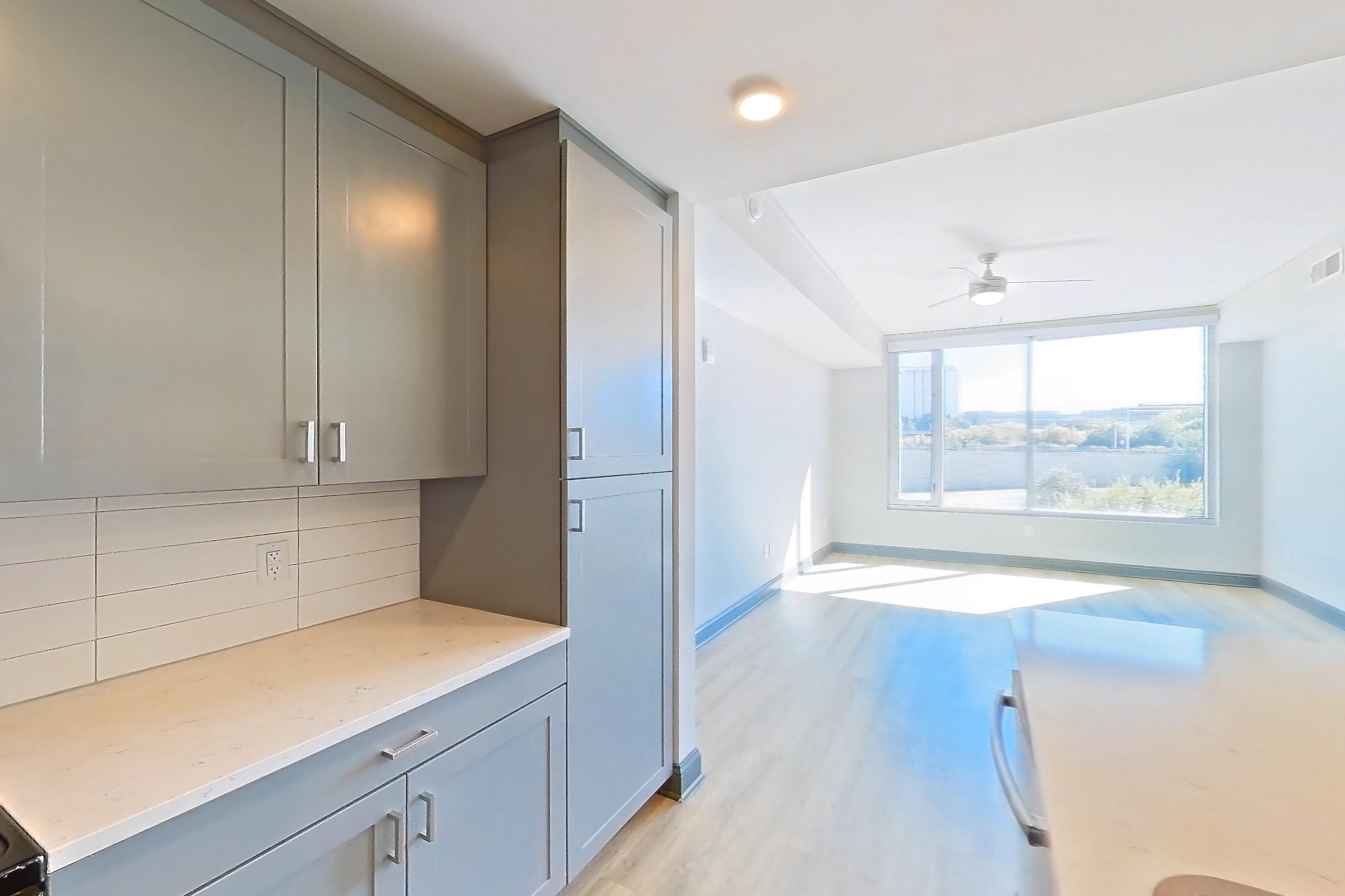 Kitchen with electric range, light countertops, light stone countertops, light wood-finish flooring, microwave, oven/range, refrigerator, stainless steel appliances, and water & ice dispenser, Apartment 234 at Cortland Glenwood South