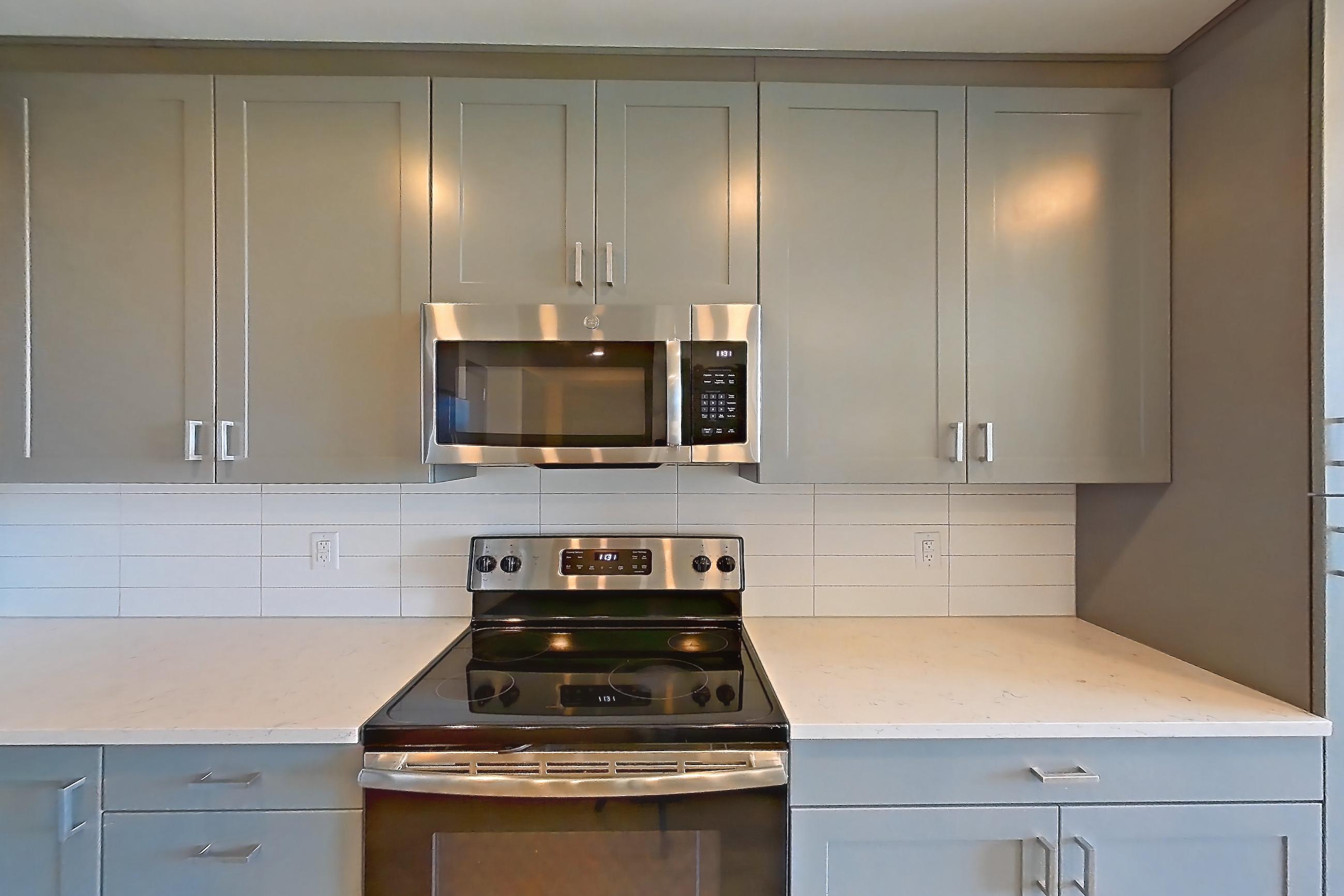 Kitchen with electric range, light countertops, light stone countertops, light wood-finish flooring, microwave, oven/range, refrigerator, stainless steel appliances, and water & ice dispenser, Apartment 234 at Cortland Glenwood South
