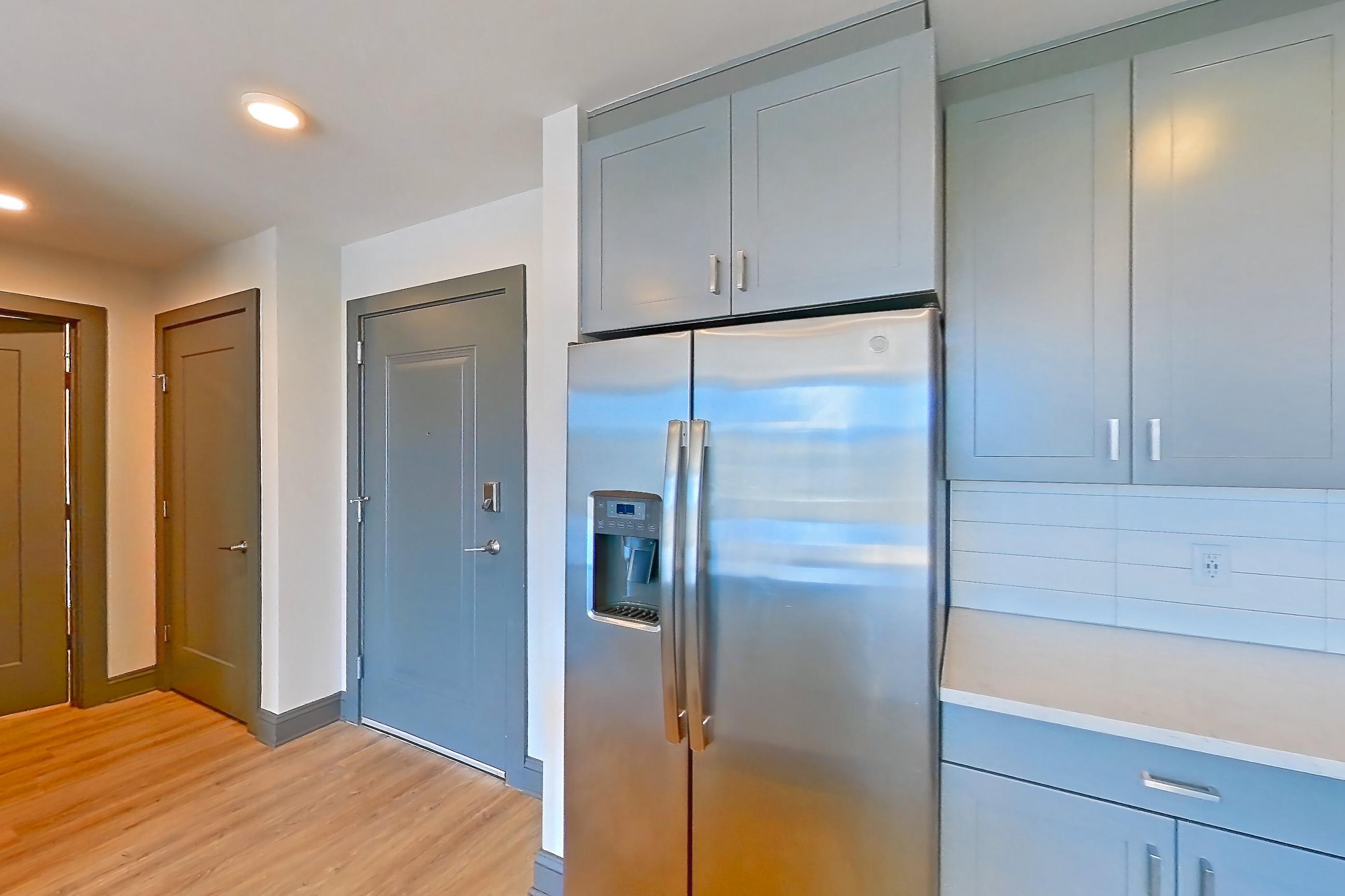 Kitchen with electric range, light countertops, light stone countertops, light wood-finish flooring, microwave, oven/range, refrigerator, stainless steel appliances, and water & ice dispenser, Apartment 234 at Cortland Glenwood South