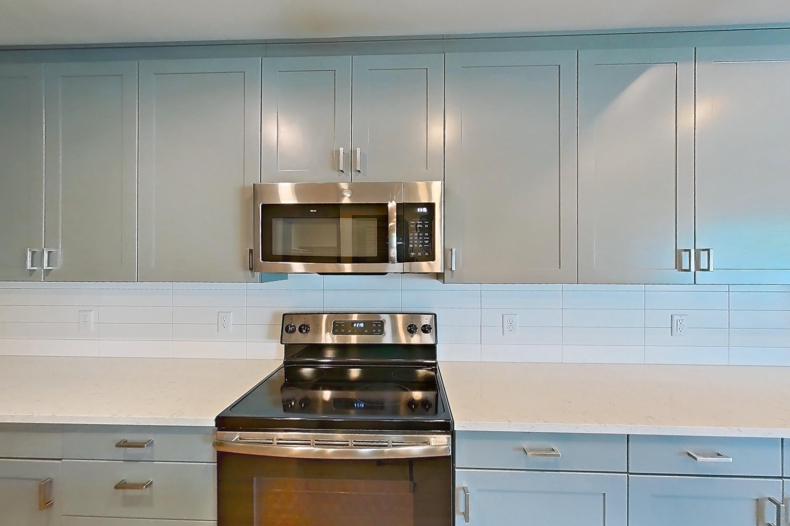 Kitchen with electric range, light countertops, light stone countertops, light wood-finish flooring, microwave, oven/range, refrigerator, stainless steel appliances, and water & ice dispenser, Apartment 426 at Cortland Glenwood South