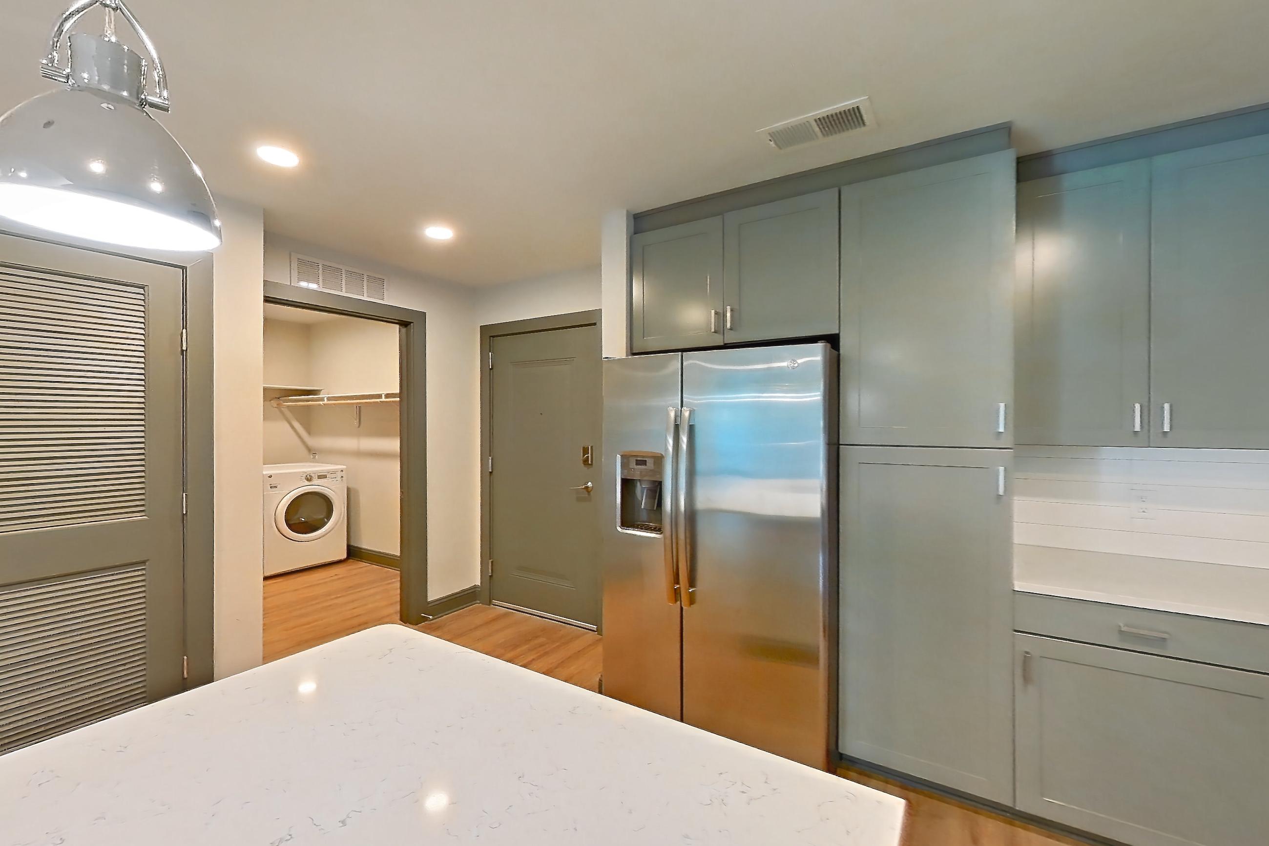 Kitchen with electric range, light countertops, light stone countertops, light wood-finish flooring, microwave, oven/range, refrigerator, stainless steel appliances, and water & ice dispenser, Apartment 426 at Cortland Glenwood South