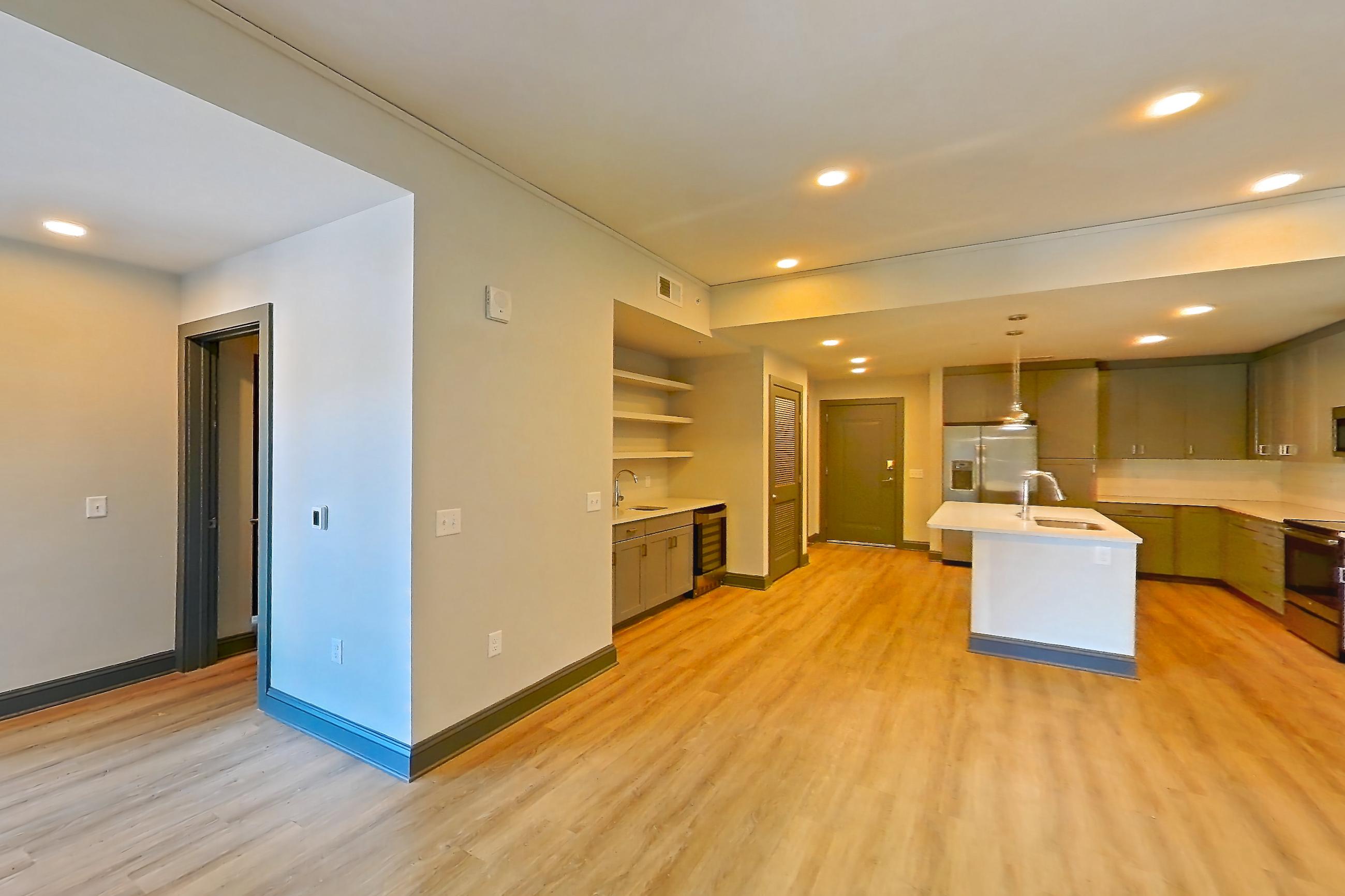 Living room with electric range, kitchen island, light countertops, light wood-finish flooring, oven/range, refrigerator, and stainless steel appliances, Apartment 426 at Cortland Glenwood South