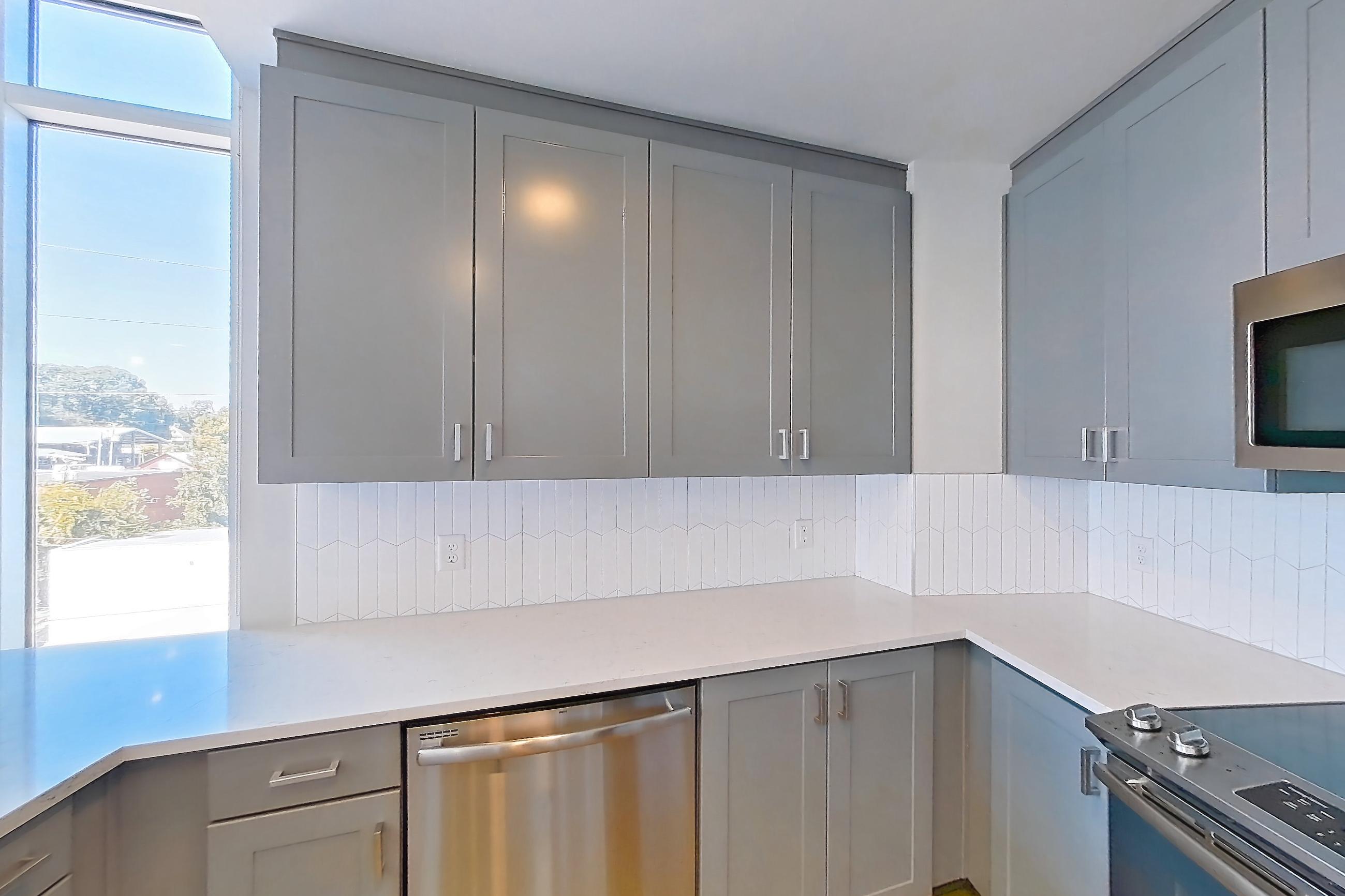 Kitchen with dishwasher, electric range, kitchen island, light countertops, light stone countertops, light wood-finish flooring, oven/range, refrigerator, stainless steel appliances, and water & ice dispenser, Apartment 430 at Cortland Glenwood South