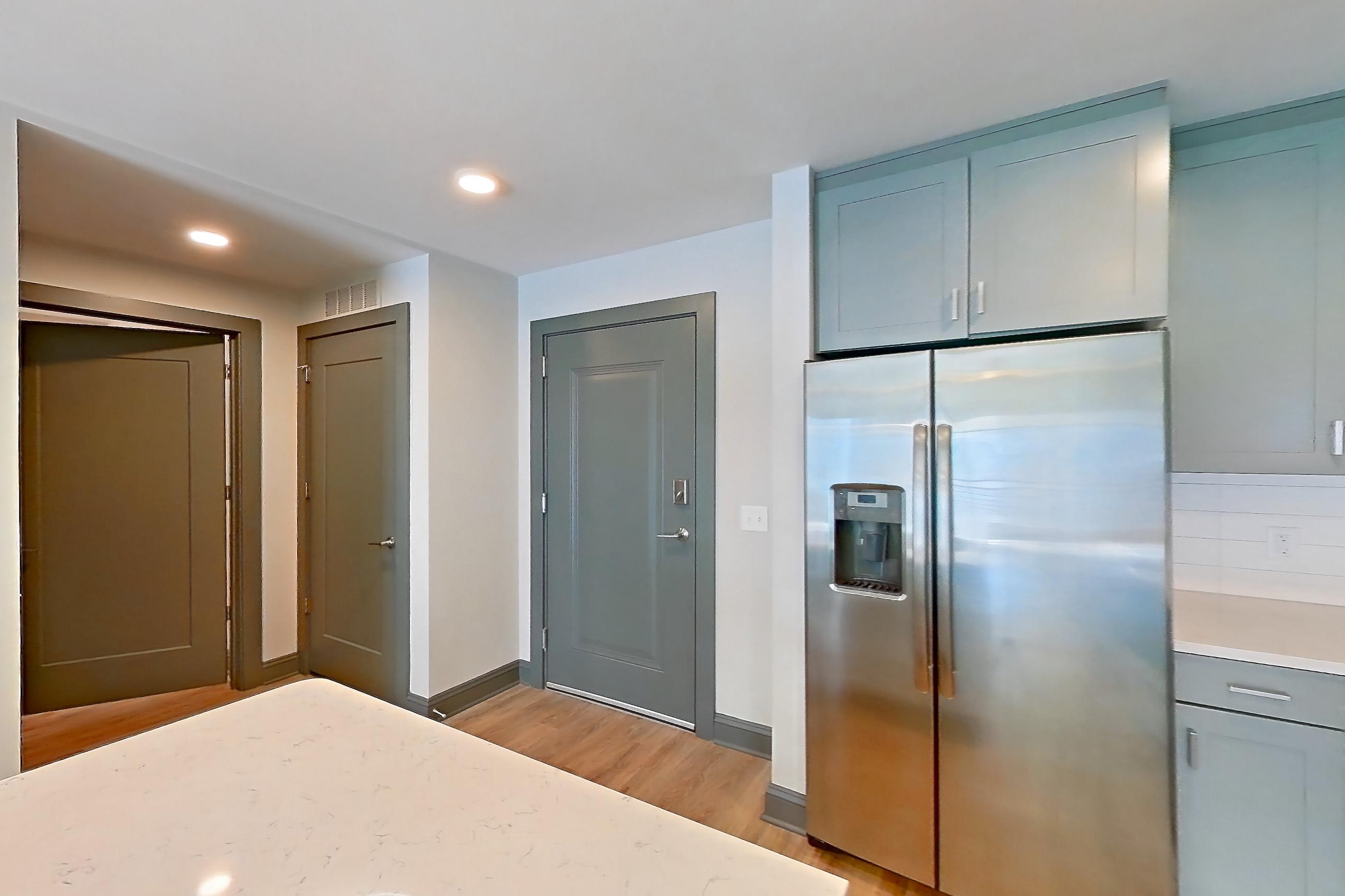 Kitchen with electric range, light countertops, light stone countertops, light wood-finish flooring, microwave, oven/range, refrigerator, stainless steel appliances, and water & ice dispenser, Apartment 813 at Cortland Glenwood South