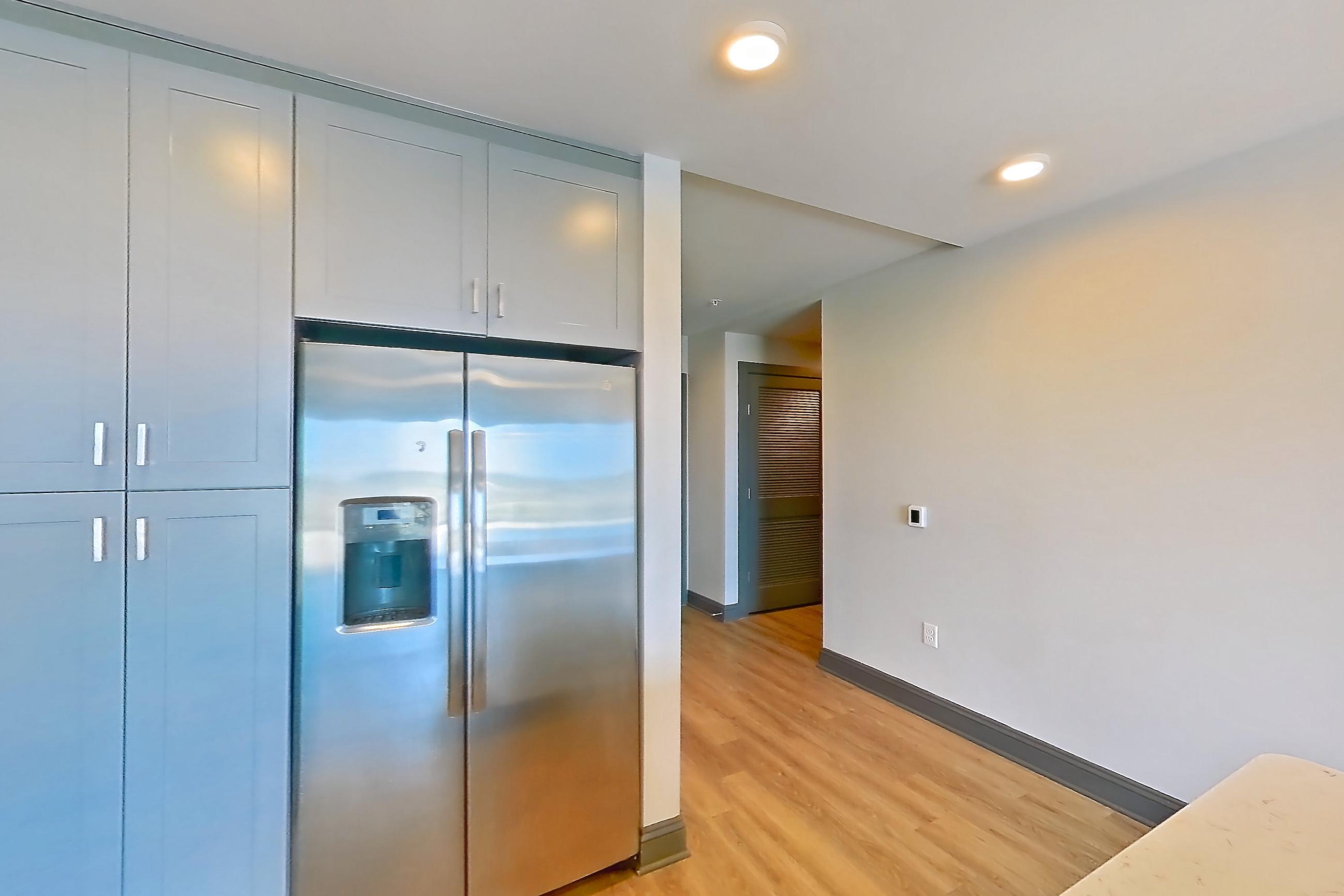 Kitchen with electric range, light countertops, light stone countertops, light wood-finish flooring, microwave, oven/range, refrigerator, stainless steel appliances, and water & ice dispenser, Apartment 816 at Cortland Glenwood South