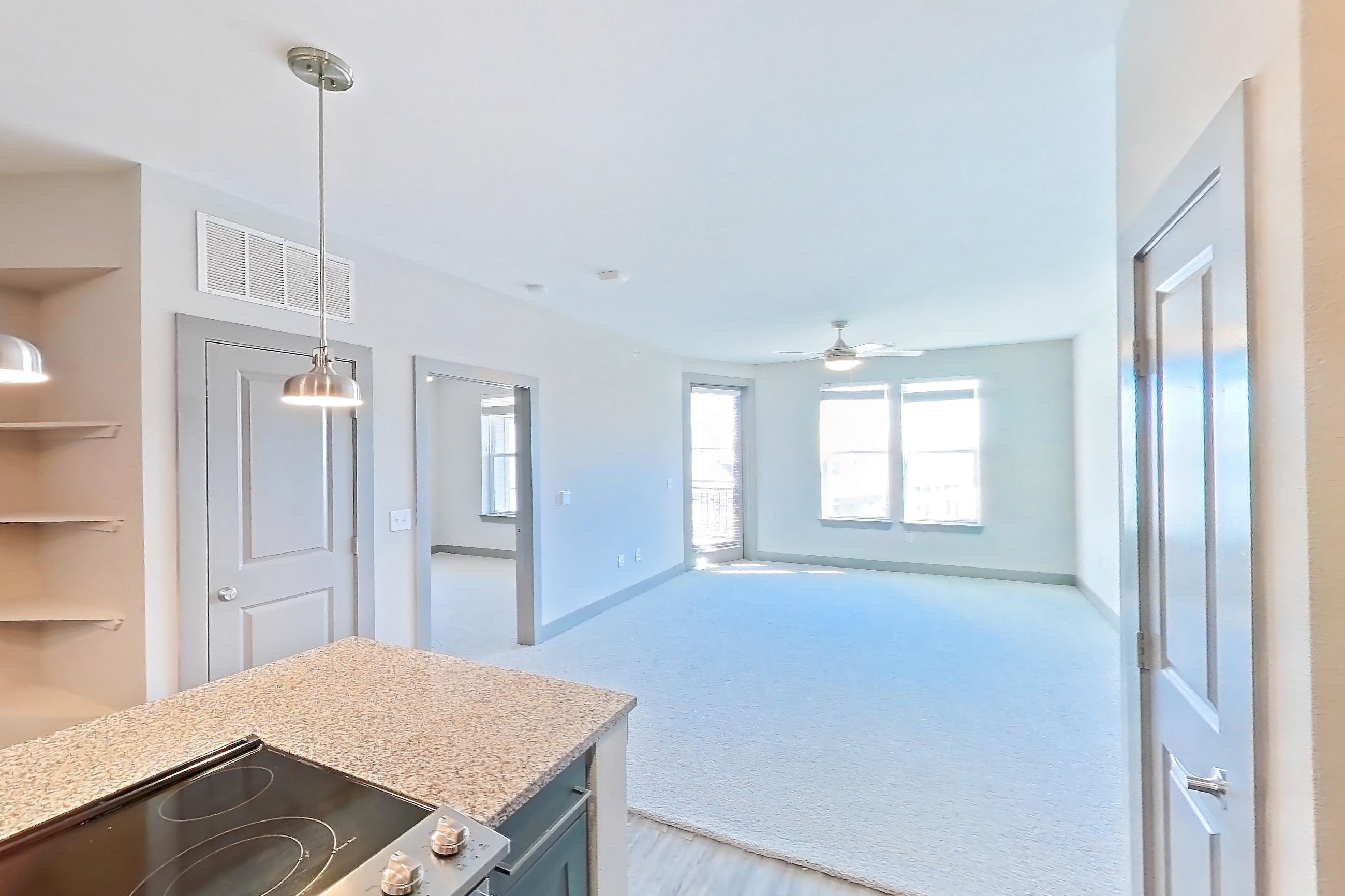 Kitchen with dishwasher, electric range, light carpet, light stone countertops, light wood-finish flooring, oven/range, refrigerator, and stainless steel appliances, Apartment 02204 at Embree Hill