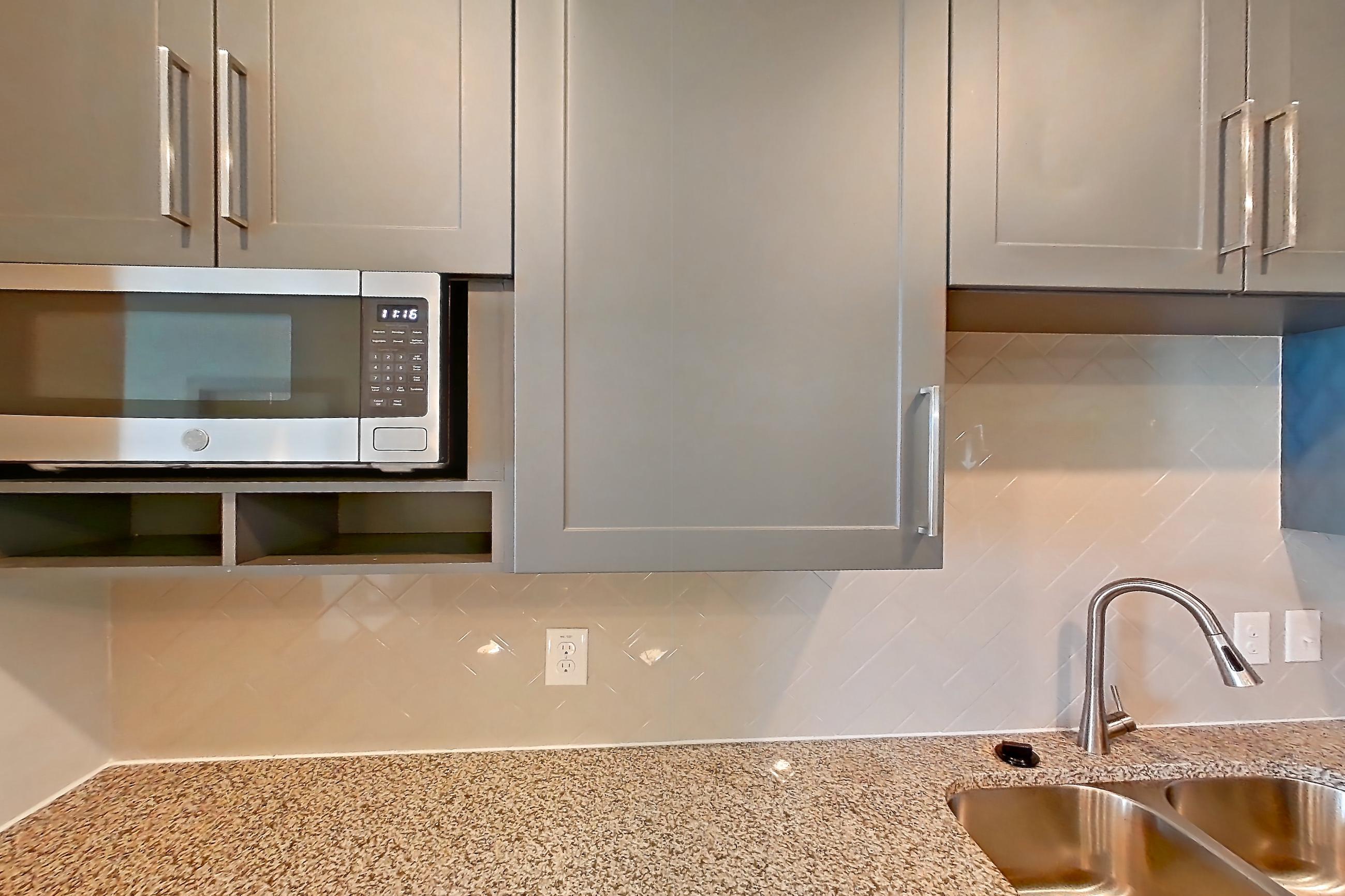 Kitchen with dishwasher, electric range, light carpet, light stone countertops, light wood-finish flooring, oven/range, refrigerator, and stainless steel appliances, Apartment 02204 at Embree Hill
