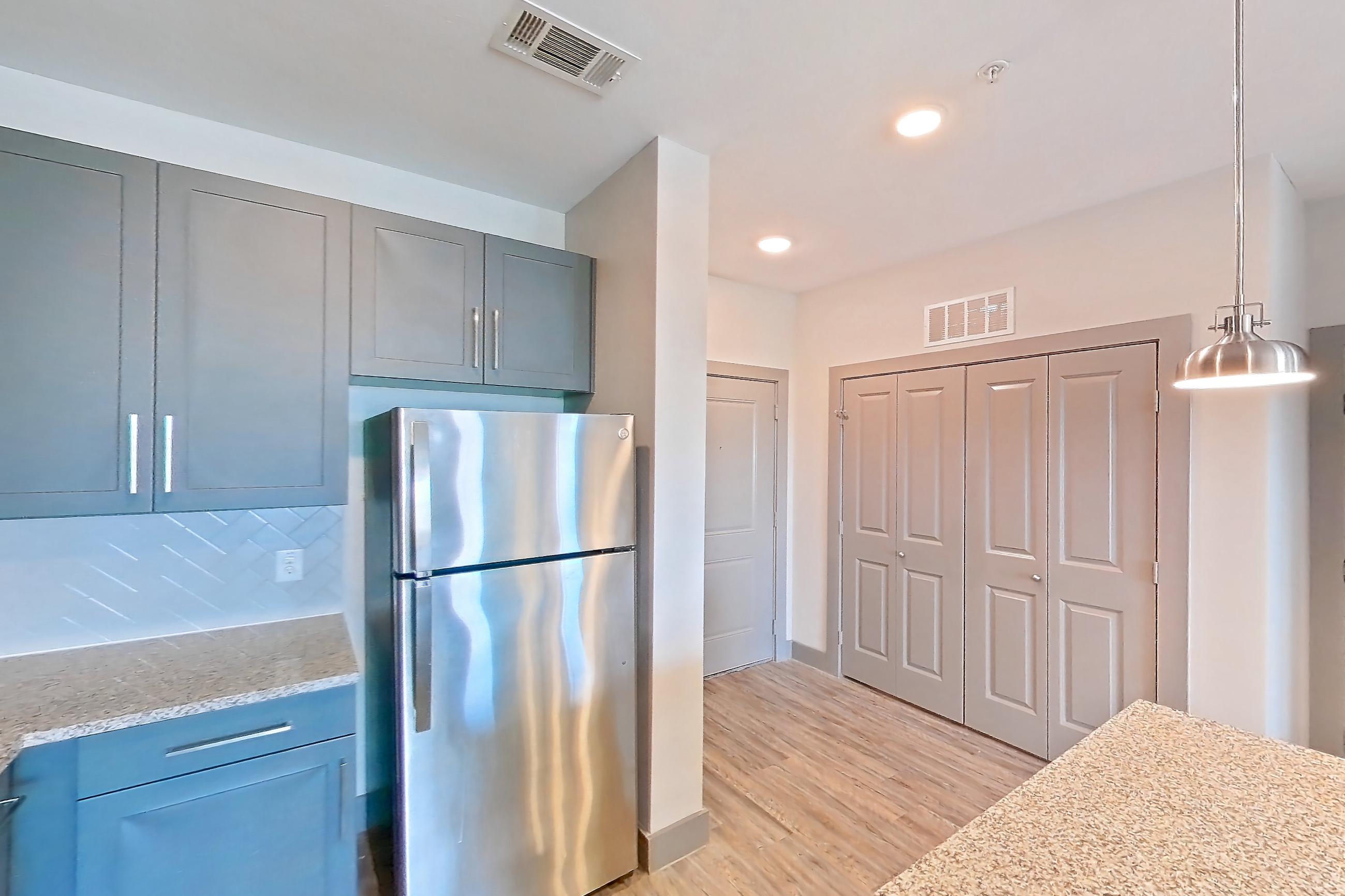 Kitchen with dishwasher, electric range, light carpet, light stone countertops, light wood-finish flooring, oven/range, refrigerator, and stainless steel appliances, Apartment 02204 at Embree Hill
