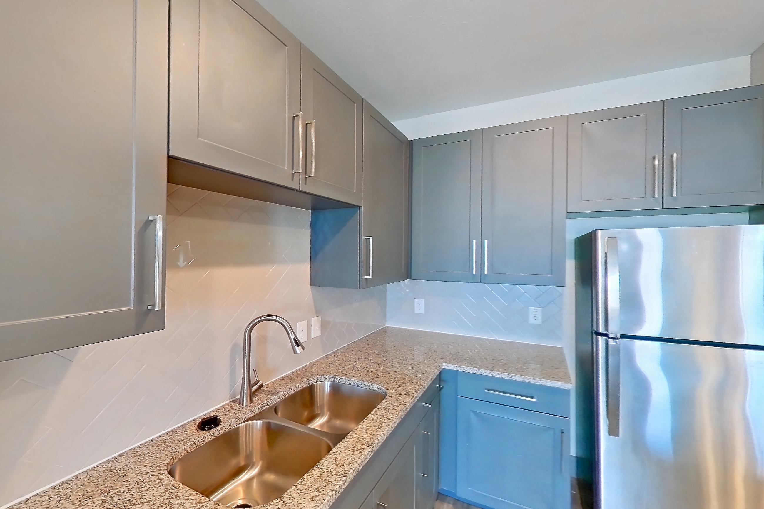 Kitchen with dishwasher, electric range, light carpet, light stone countertops, light wood-finish flooring, oven/range, refrigerator, and stainless steel appliances, Apartment 02204 at Embree Hill