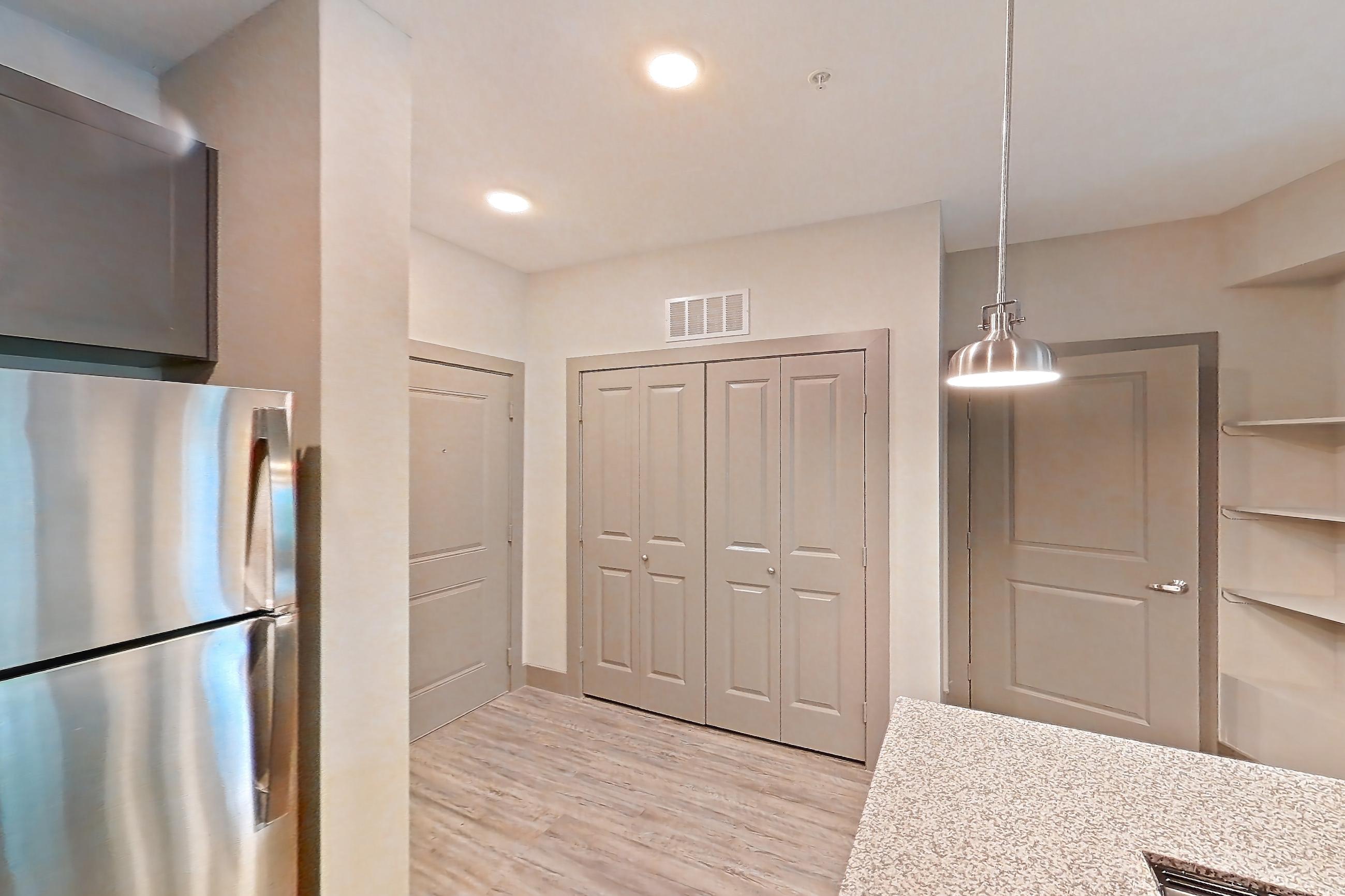 Kitchen with dishwasher, electric range, light countertops, light stone countertops, light wood-finish flooring, microwave, oven/range, refrigerator, and stainless steel appliances, Apartment 05104 at Embree Hill