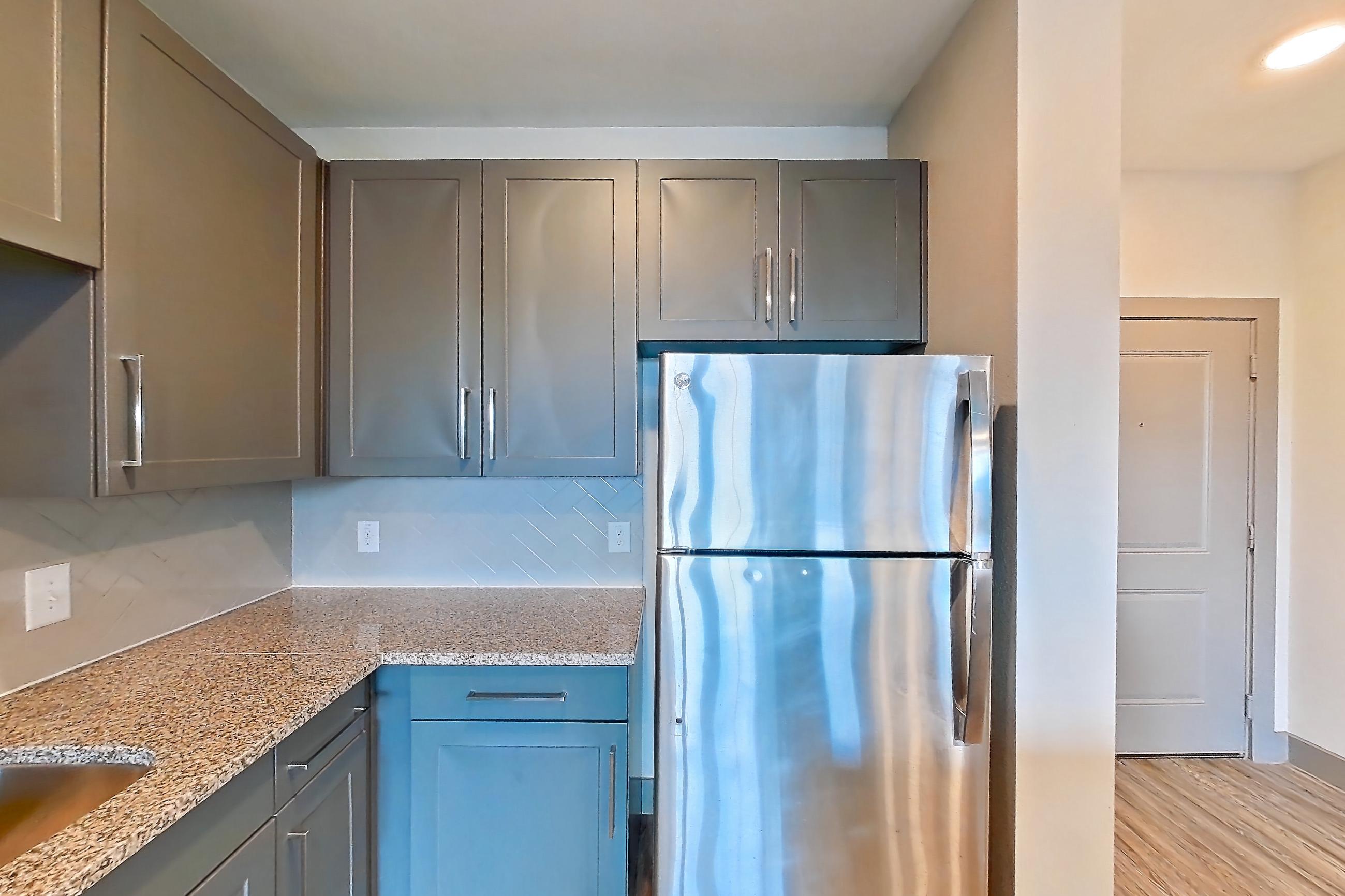 Kitchen with dishwasher, electric range, light countertops, light stone countertops, light wood-finish flooring, microwave, oven/range, refrigerator, and stainless steel appliances, Apartment 05205 at Embree Hill