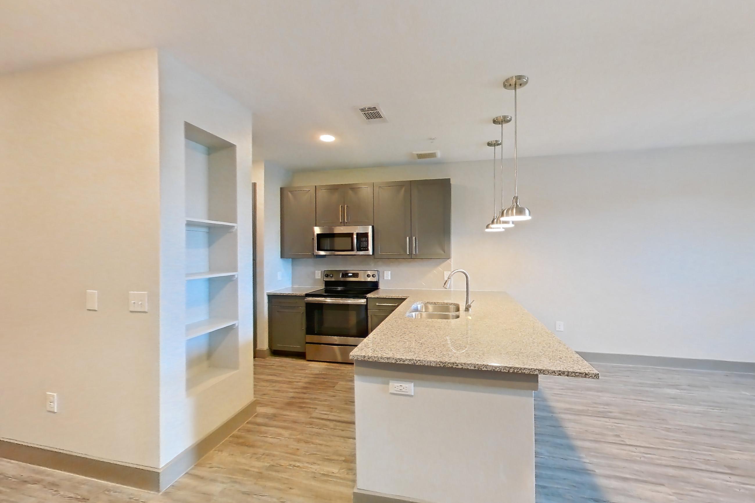 Dining room with electric range, light stone countertops, light wood-finish flooring, microwave, oven/range, and stainless steel appliances, Apartment 05103 at Embree Hill