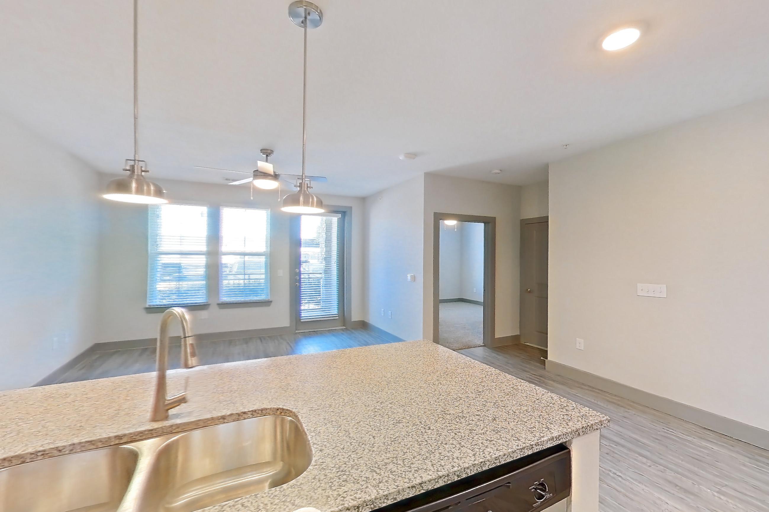 Kitchen with dishwasher, electric range, light countertops, light stone countertops, light wood-finish flooring, microwave, oven/range, refrigerator, and stainless steel appliances, Apartment 05103 at Embree Hill