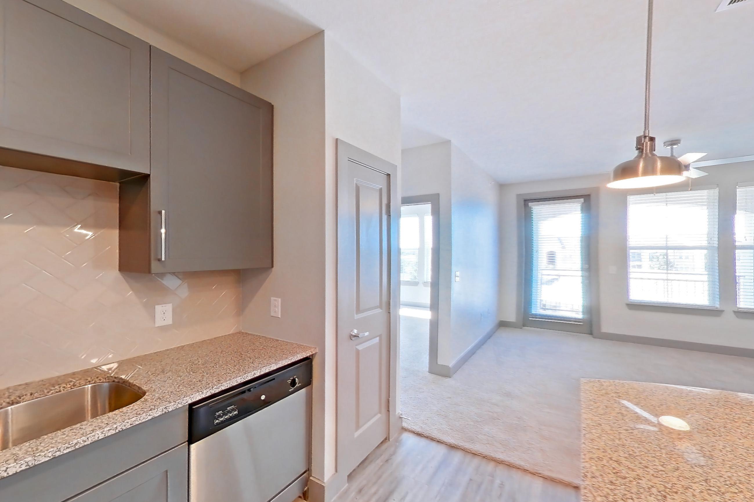 Kitchen with dishwasher, electric range, light carpet, light stone countertops, light wood-finish flooring, microwave, oven/range, refrigerator, and stainless steel appliances, Apartment 05302 at Embree Hill