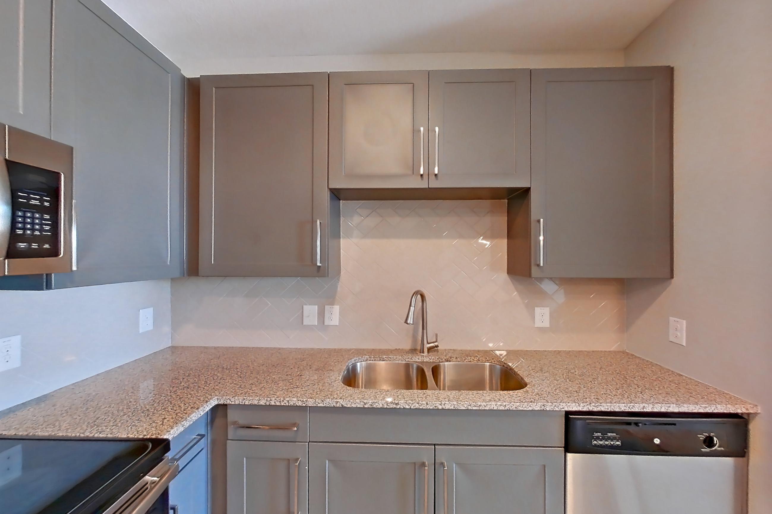 Kitchen with dishwasher, electric range, light carpet, light stone countertops, light wood-finish flooring, microwave, oven/range, refrigerator, and stainless steel appliances, Apartment 05302 at Embree Hill