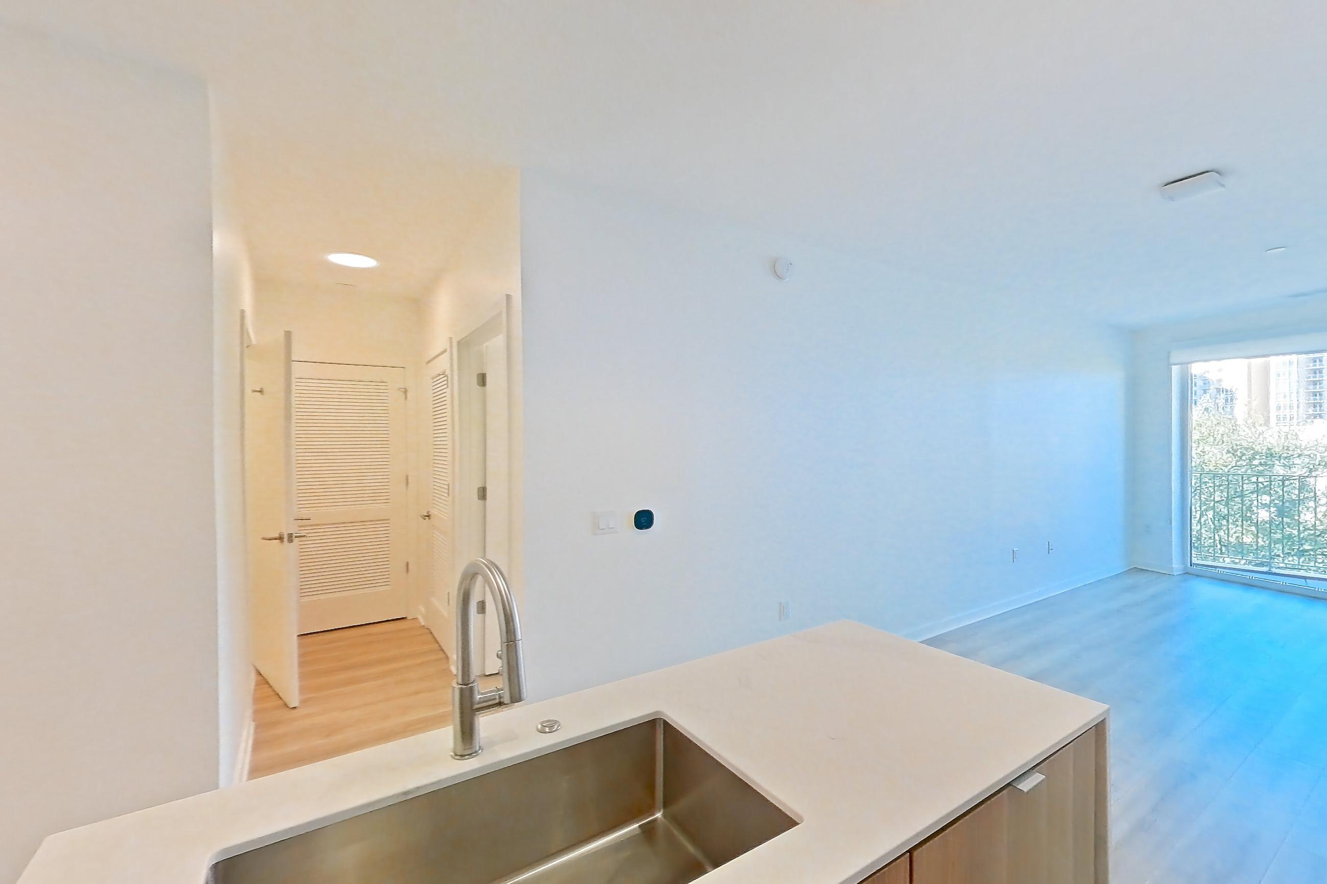 Kitchen with electric range, kitchen island, light countertops, light stone countertops, light wood-finish flooring, microwave, oven/range, and stainless steel appliances, Apartment 416 at Residences at Mazza