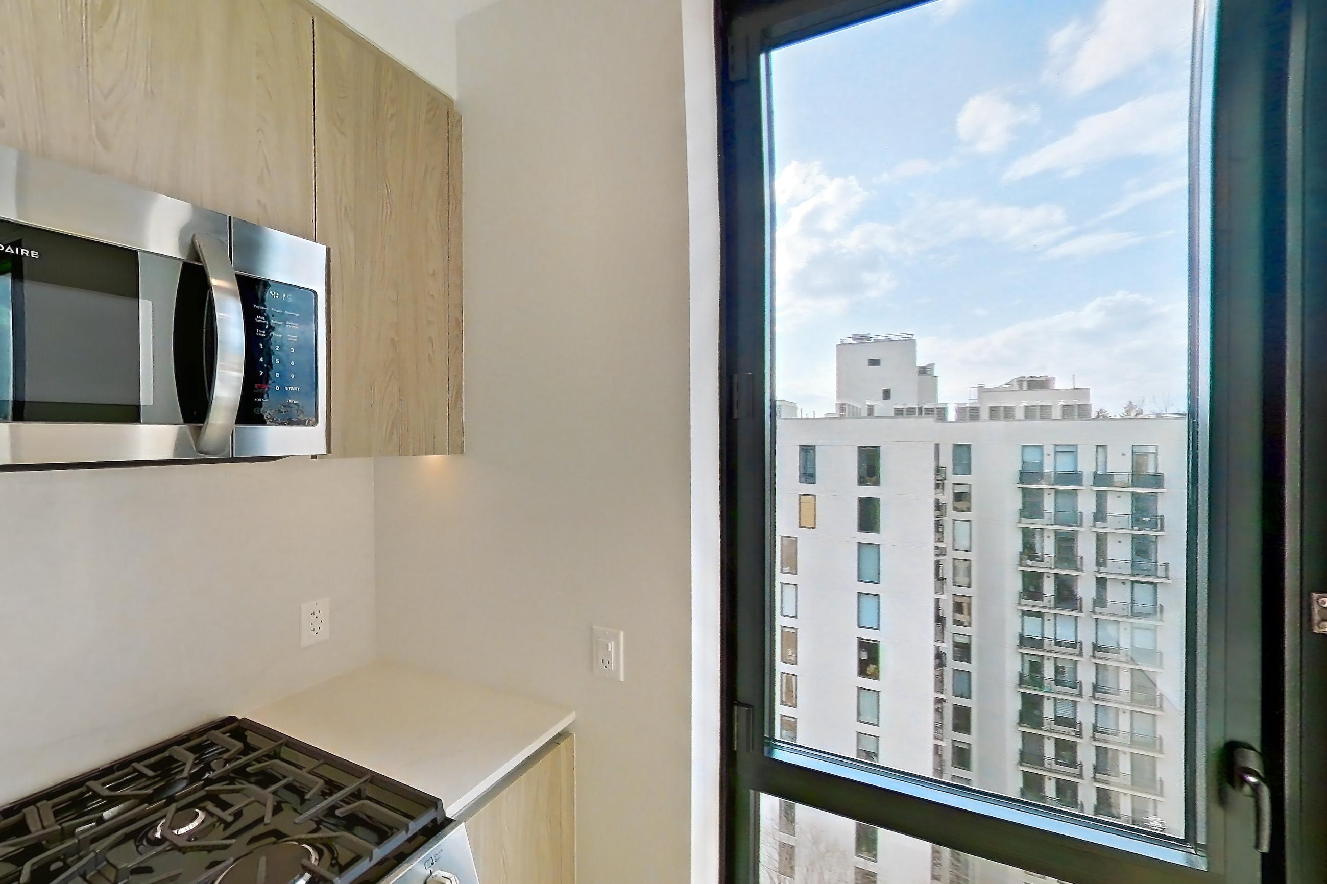 Kitchen with city view, gas range, light wood-finish flooring, oven/range, and stainless steel appliances, Apartment 1238 at Loden