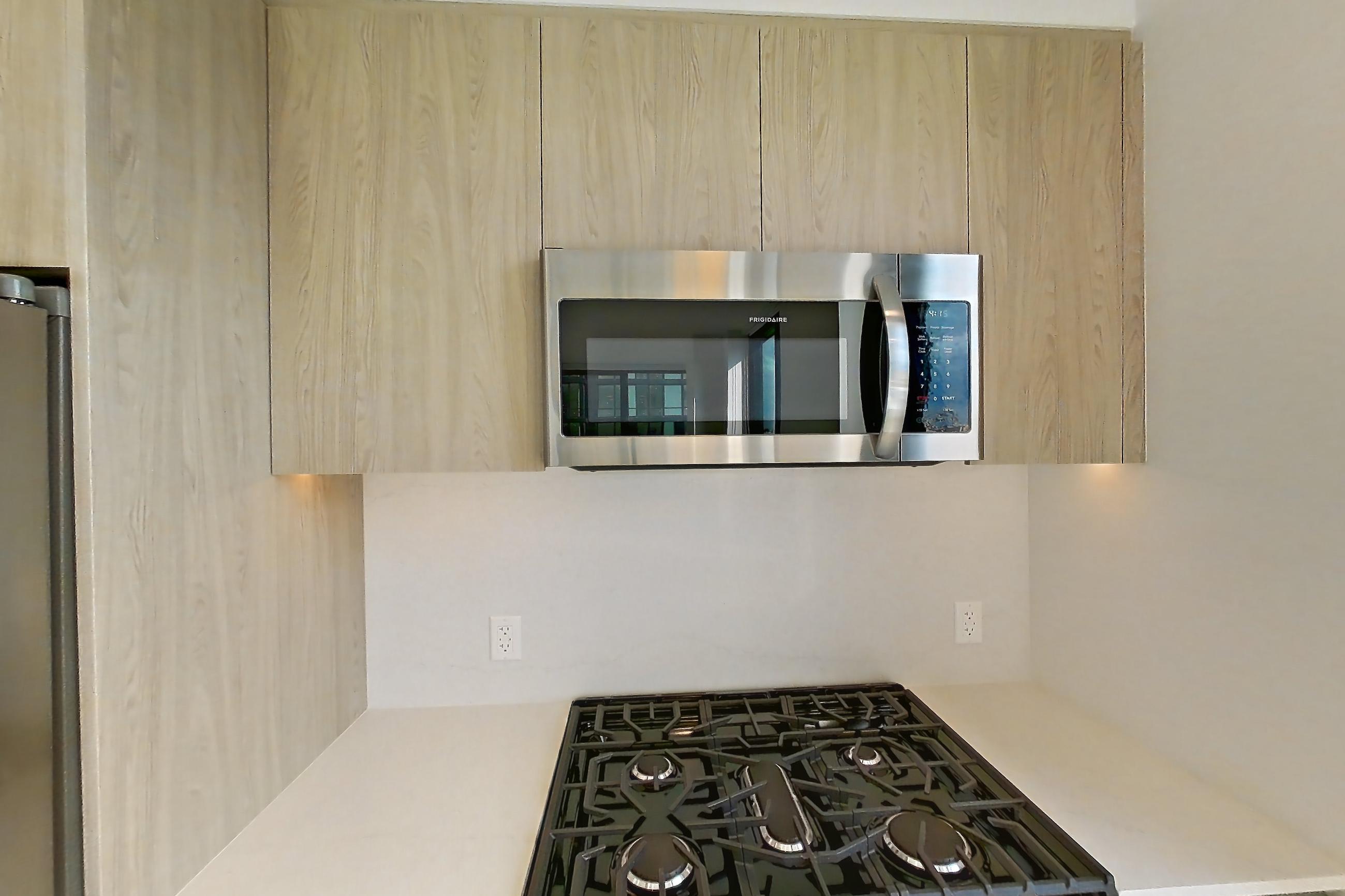 Kitchen with city view, gas range, light wood-finish flooring, oven/range, and stainless steel appliances, Apartment 1238 at Loden