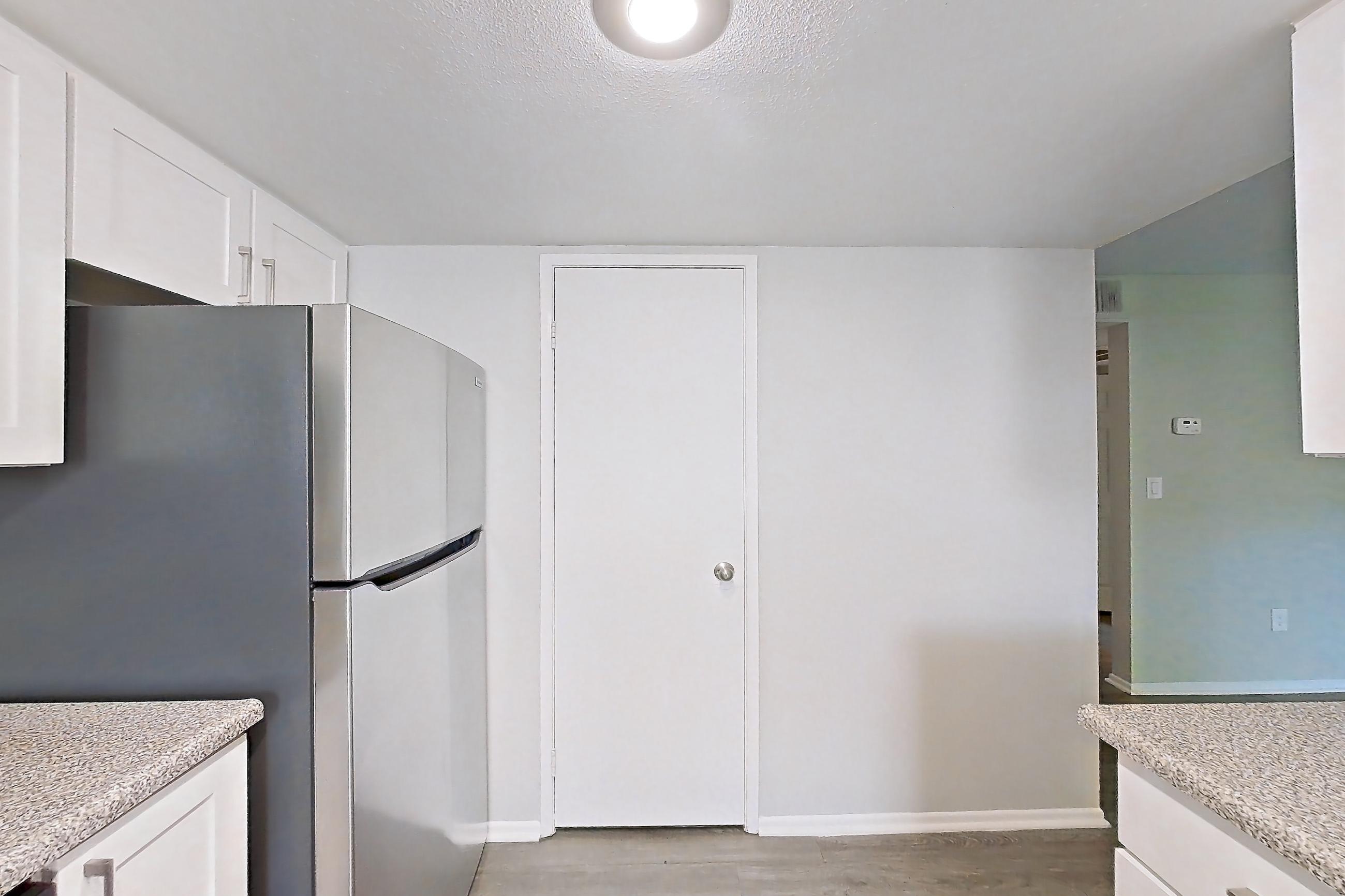 Kitchen with dishwasher, electric range, light countertops, light stone countertops, light wood-finish flooring, microwave, oven/range, range hood, refrigerator, and stainless steel appliances, Apartment 09 at Avana Rancho Cucamonga