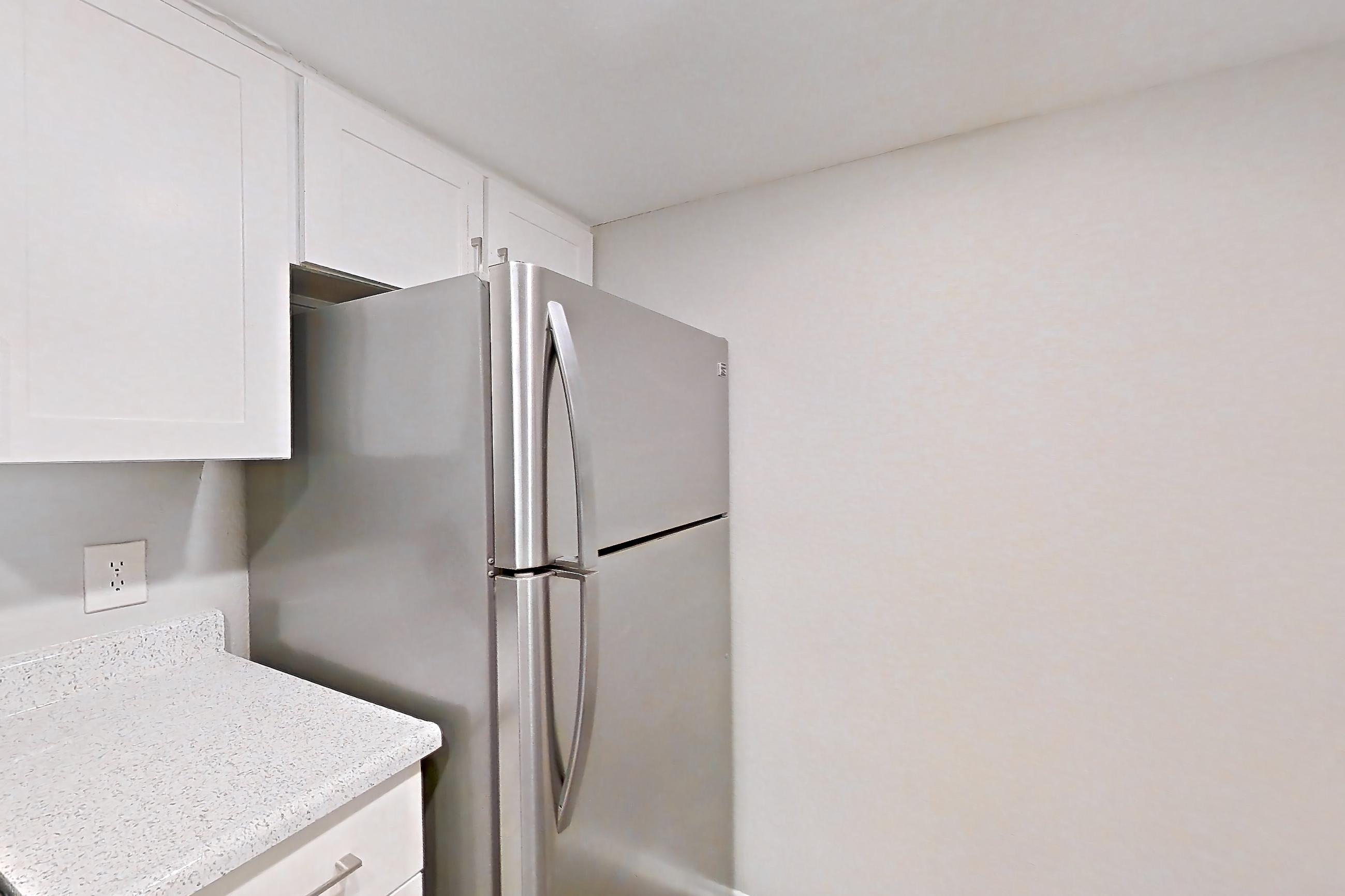 Kitchen with dishwasher, electric range, light countertops, light stone countertops, light wood-finish flooring, oven/range, range hood, refrigerator, and stainless steel appliances, Apartment 12 at Avana Rancho Cucamonga