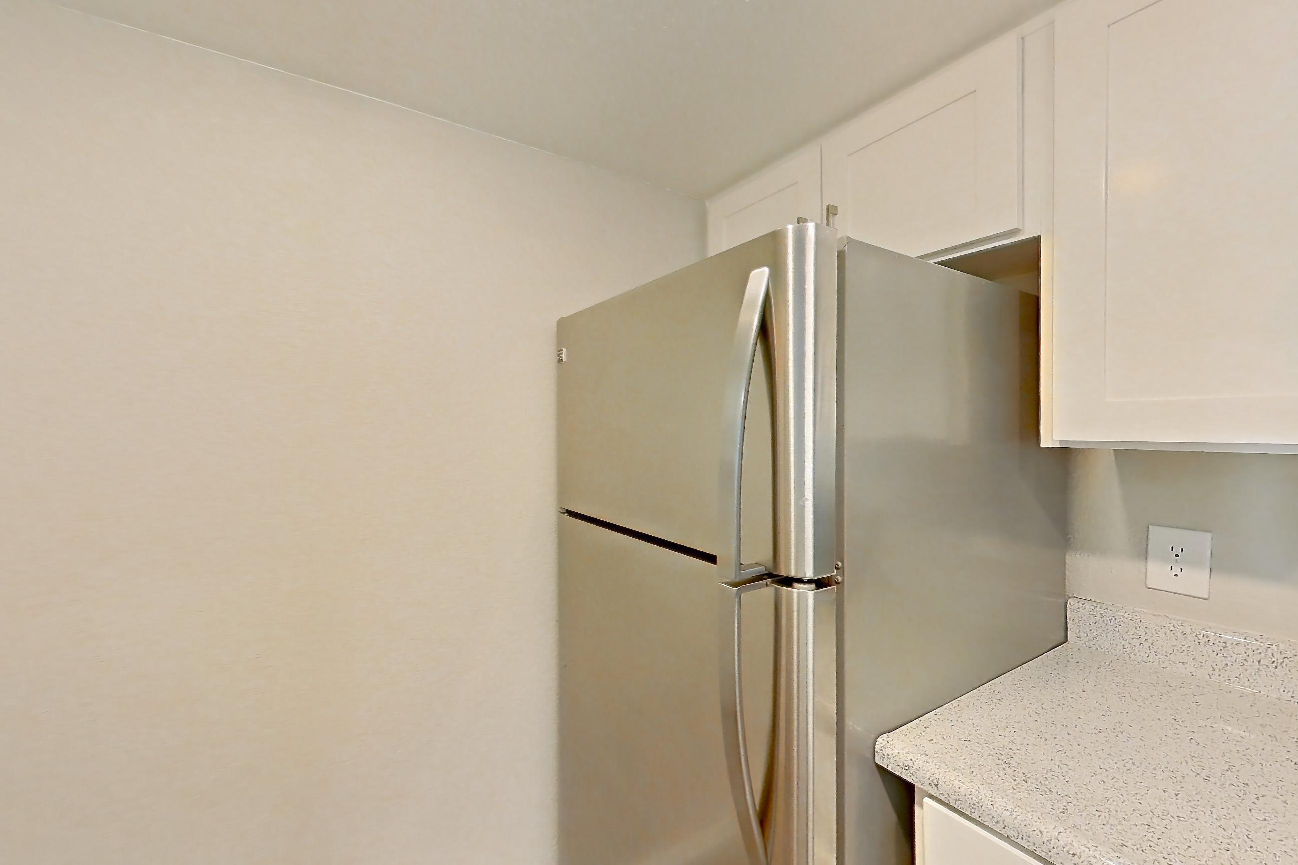 Kitchen with dishwasher, electric range, light stone countertops, light wood-finish flooring, microwave, refrigerator, and stainless steel appliances, Apartment 10 at Avana Rancho Cucamonga