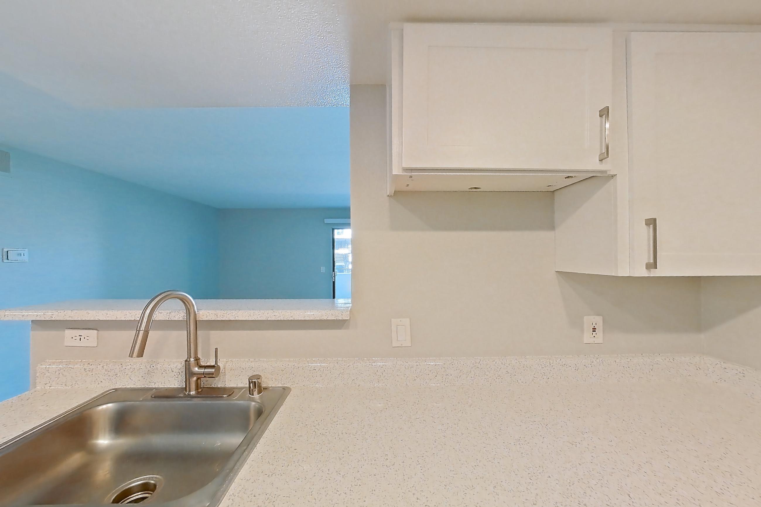 Kitchen with dishwasher, light stone countertops, light wood-finish flooring, oven/range, refrigerator, stainless steel appliances, and white appliances, Apartment 07 at Avana Rancho Cucamonga