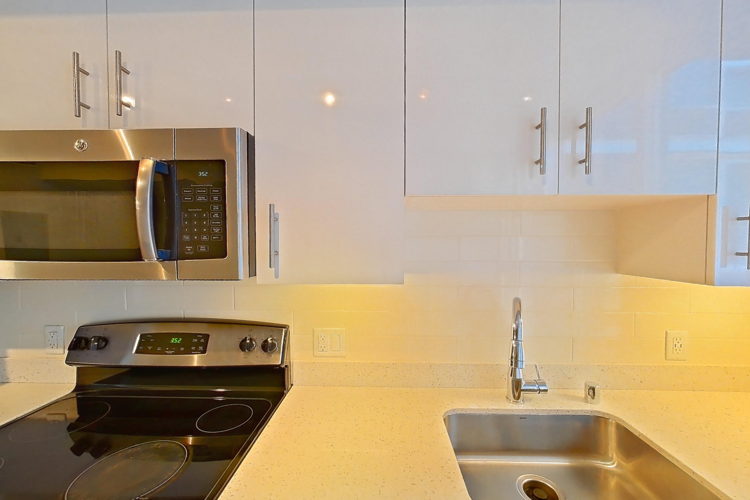 Kitchen with dishwasher, electric range, light countertops, light stone countertops, light wood-finish flooring, oven/range, refrigerator, and stainless steel appliances, Apartment 0-0805 at Cielo