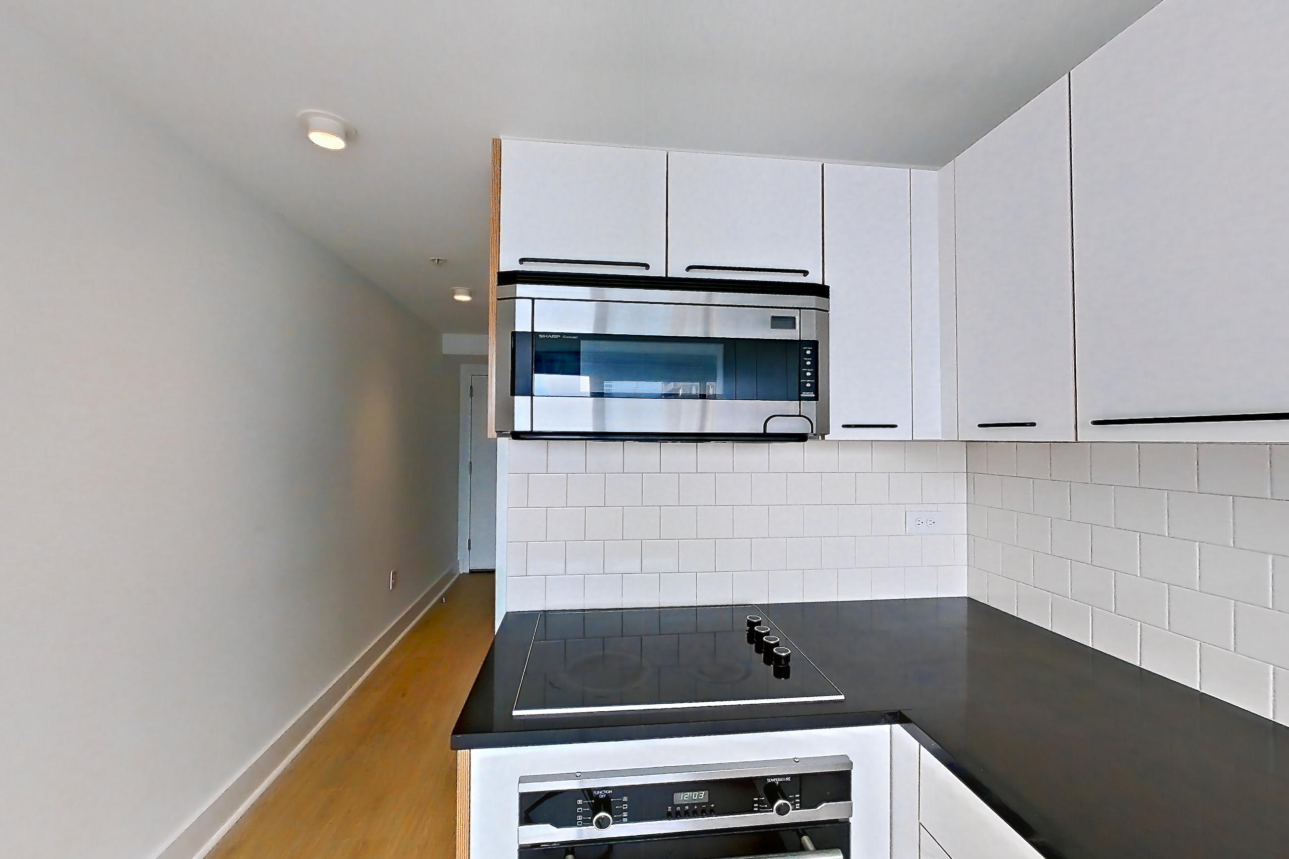 Kitchen with dark stone countertops and light wood-finish flooring, Apartment SAB-1704 at Sable