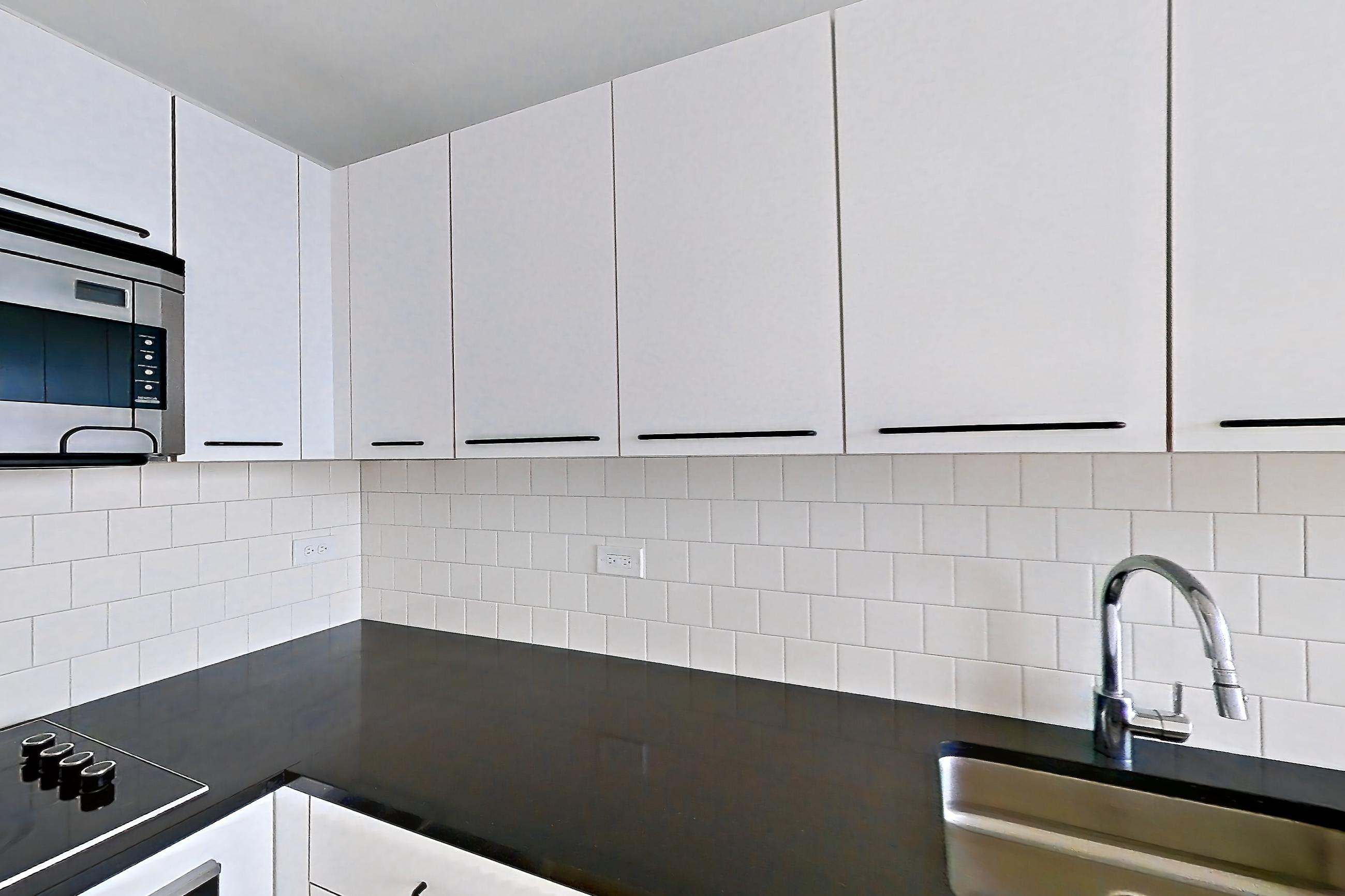 Kitchen with dark stone countertops and light wood-finish flooring, Apartment SAB-1704 at Sable