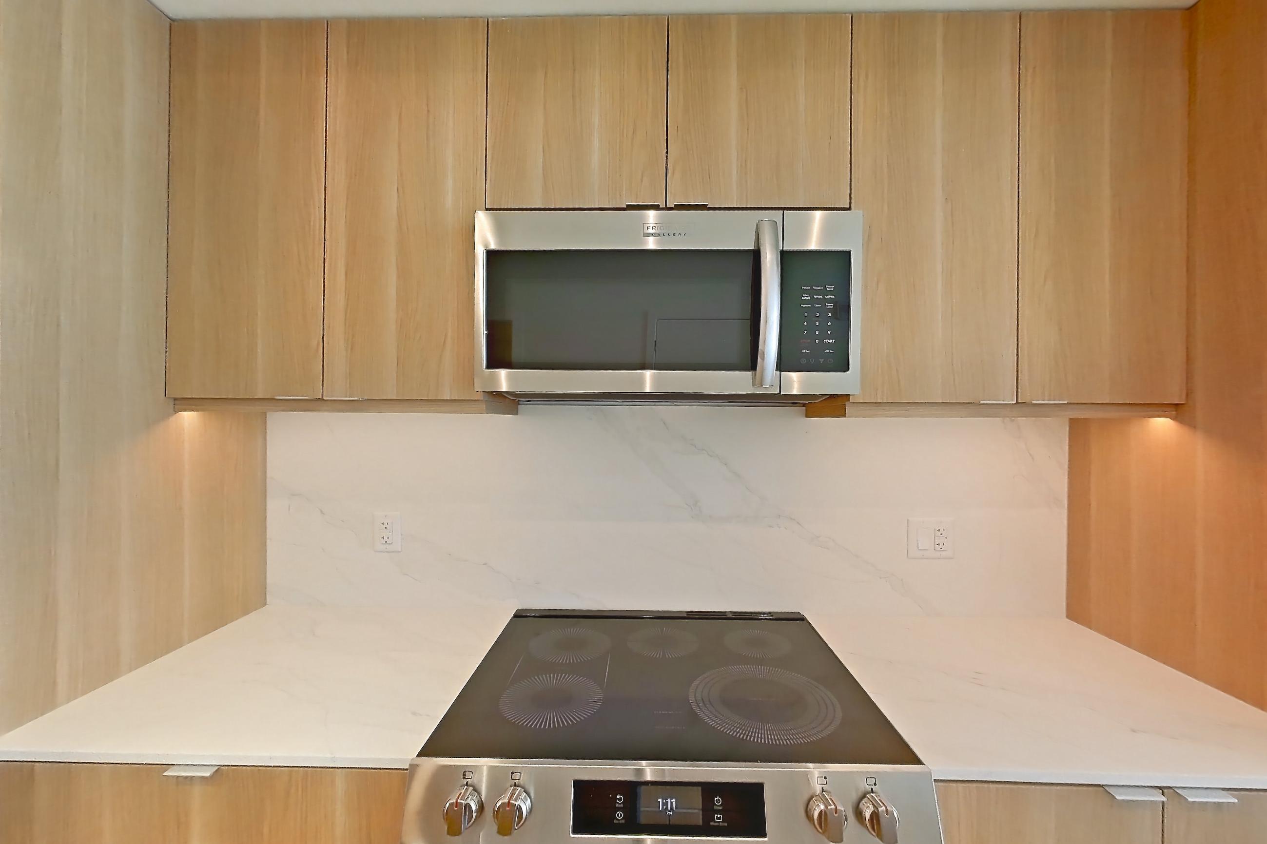 Kitchen with electric range, light stone countertops, light wood-finish flooring, oven/range, and stainless steel appliances, Apartment 625 at Residences at Mazza