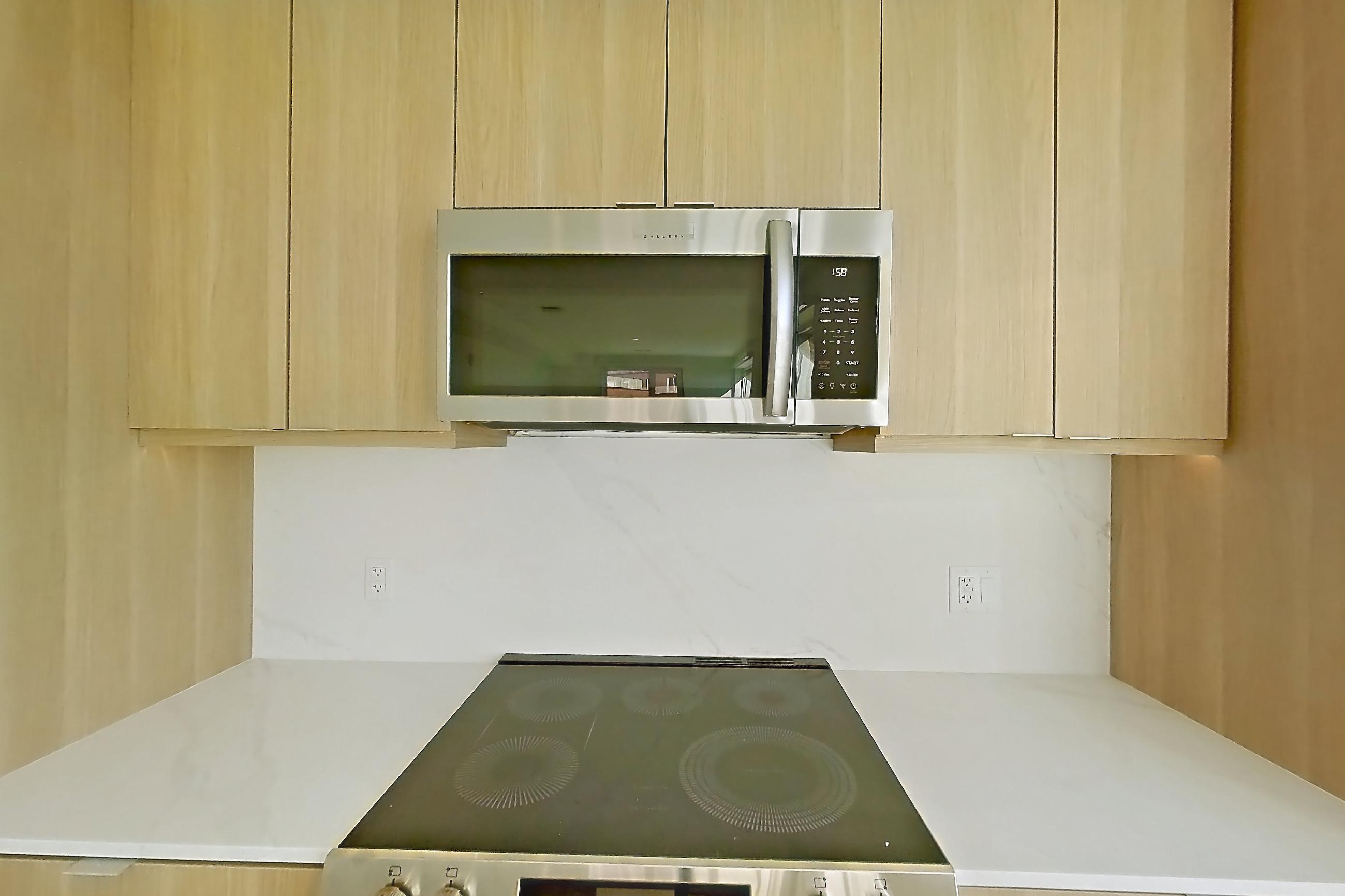 Kitchen with electric range, light stone countertops, light wood-finish flooring, oven/range, and stainless steel appliances, Apartment 657 at Residences at Mazza