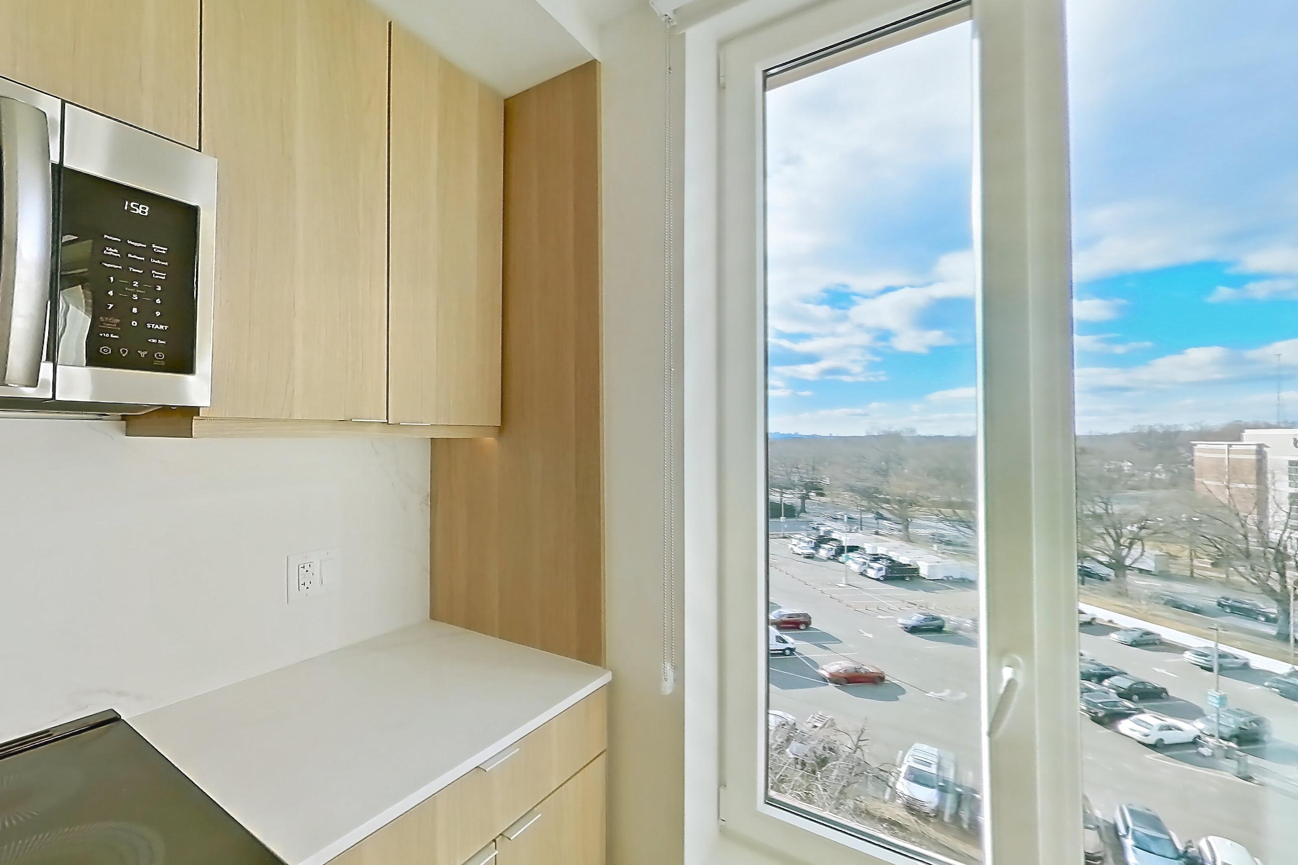 Kitchen with electric range, light stone countertops, light wood-finish flooring, oven/range, and stainless steel appliances, Apartment 657 at Residences at Mazza