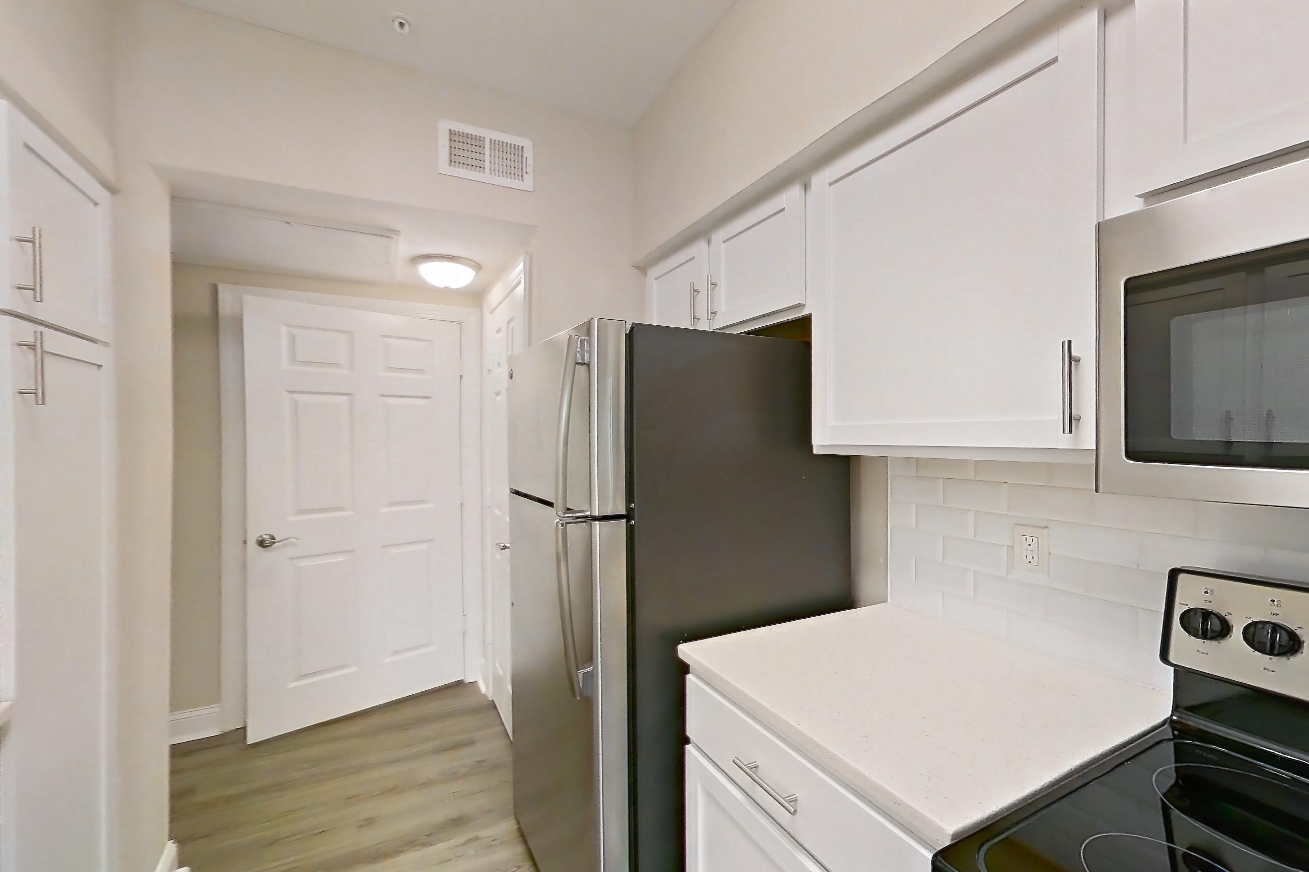 Kitchen with dishwasher, electric range, light countertops, light stone countertops, light wood-finish flooring, oven/range, refrigerator, and stainless steel appliances, Apartment 4314 at Marq Perimeter
