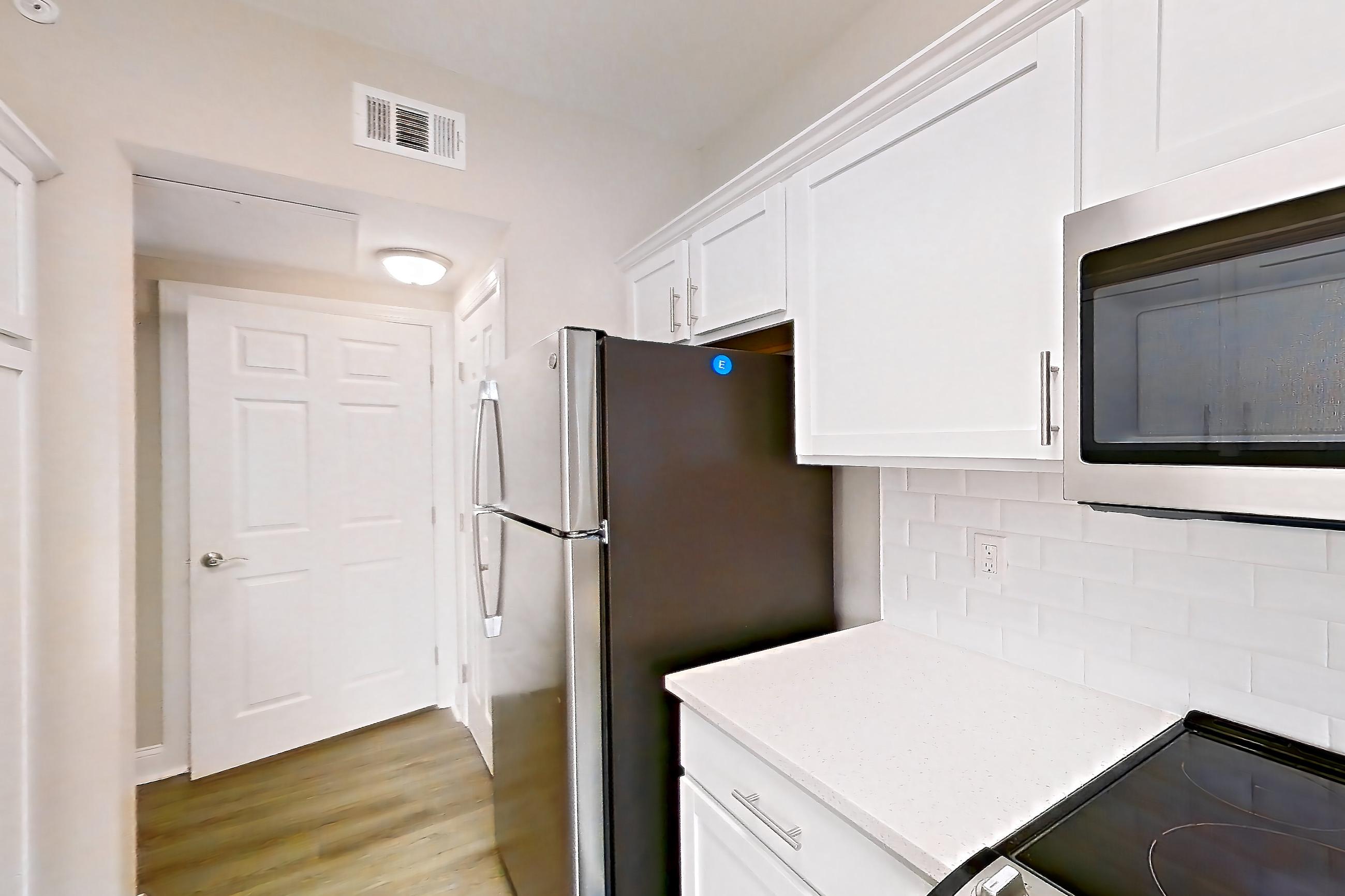 Kitchen with electric range, light countertops, light stone countertops, light wood-finish flooring, oven/range, refrigerator, and stainless steel appliances, Apartment 4514 at Marq Perimeter