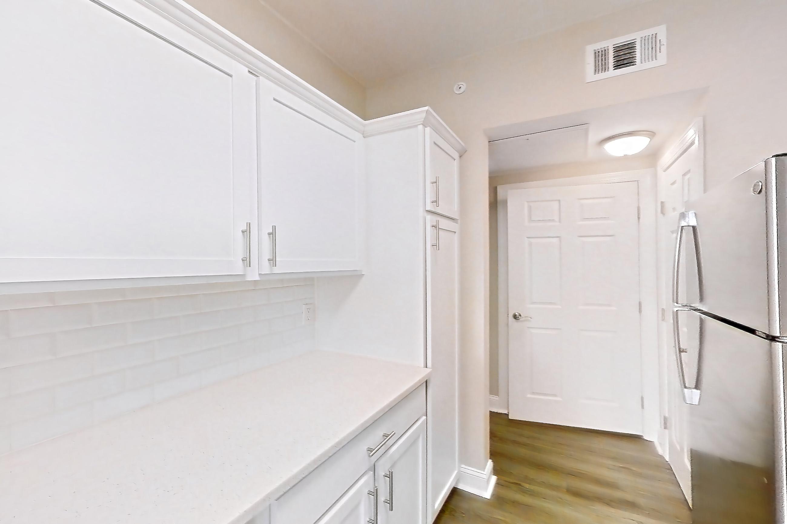 Kitchen with electric range, light countertops, light stone countertops, light wood-finish flooring, oven/range, refrigerator, and stainless steel appliances, Apartment 4514 at Marq Perimeter