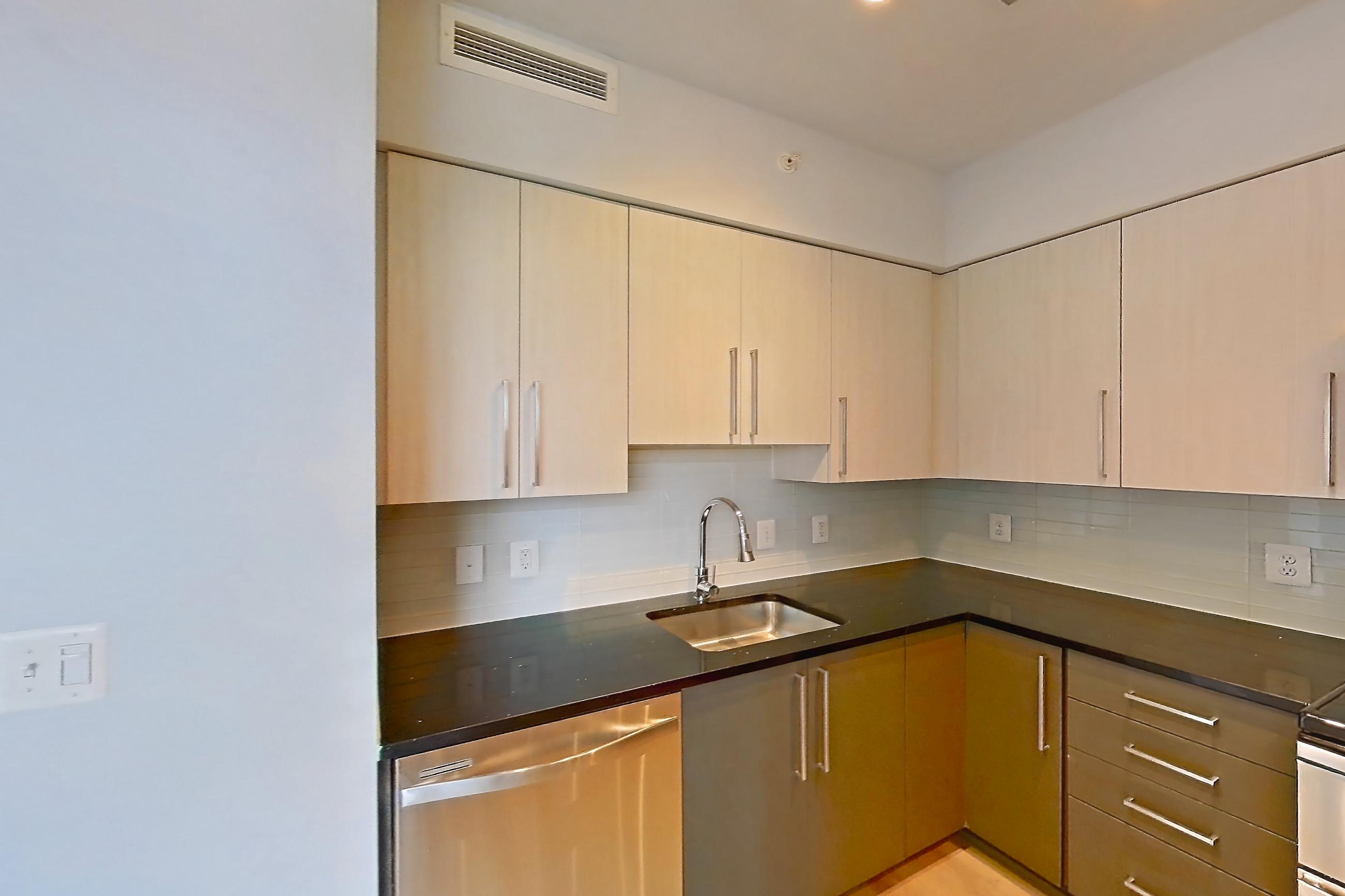 Kitchen with dark stone countertops, dishwasher, double oven, electric range, light countertops, light wood-finish flooring, microwave, oven/range, refrigerator, stainless steel appliances, and water & ice dispenser, Apartment 0316 at Latitude
