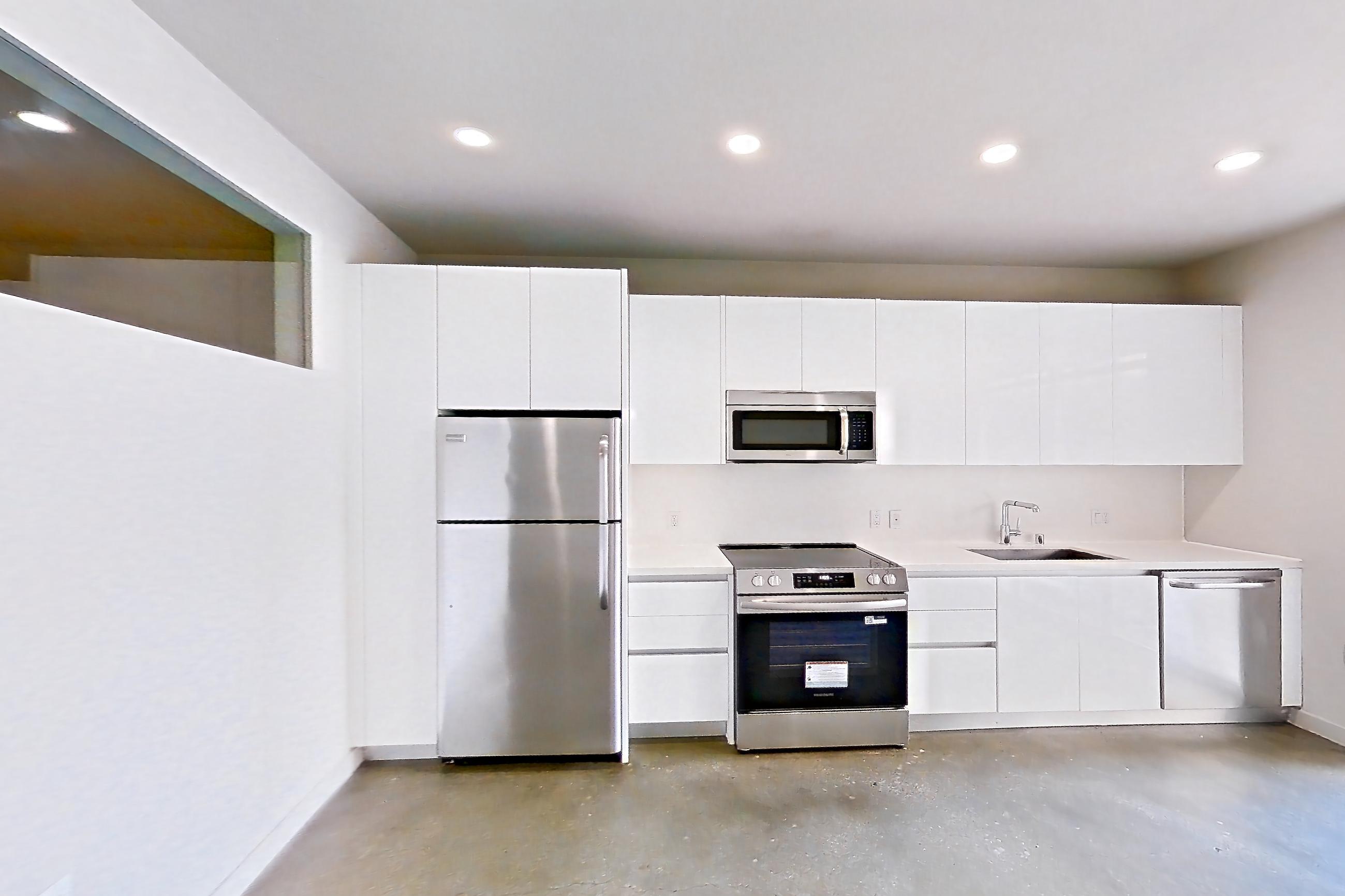 Living room with electric range, light countertops, oven/range, polished concrete flooring, refrigerator, and stainless steel appliances, Apartment 0-2077 at Eighth and Grand