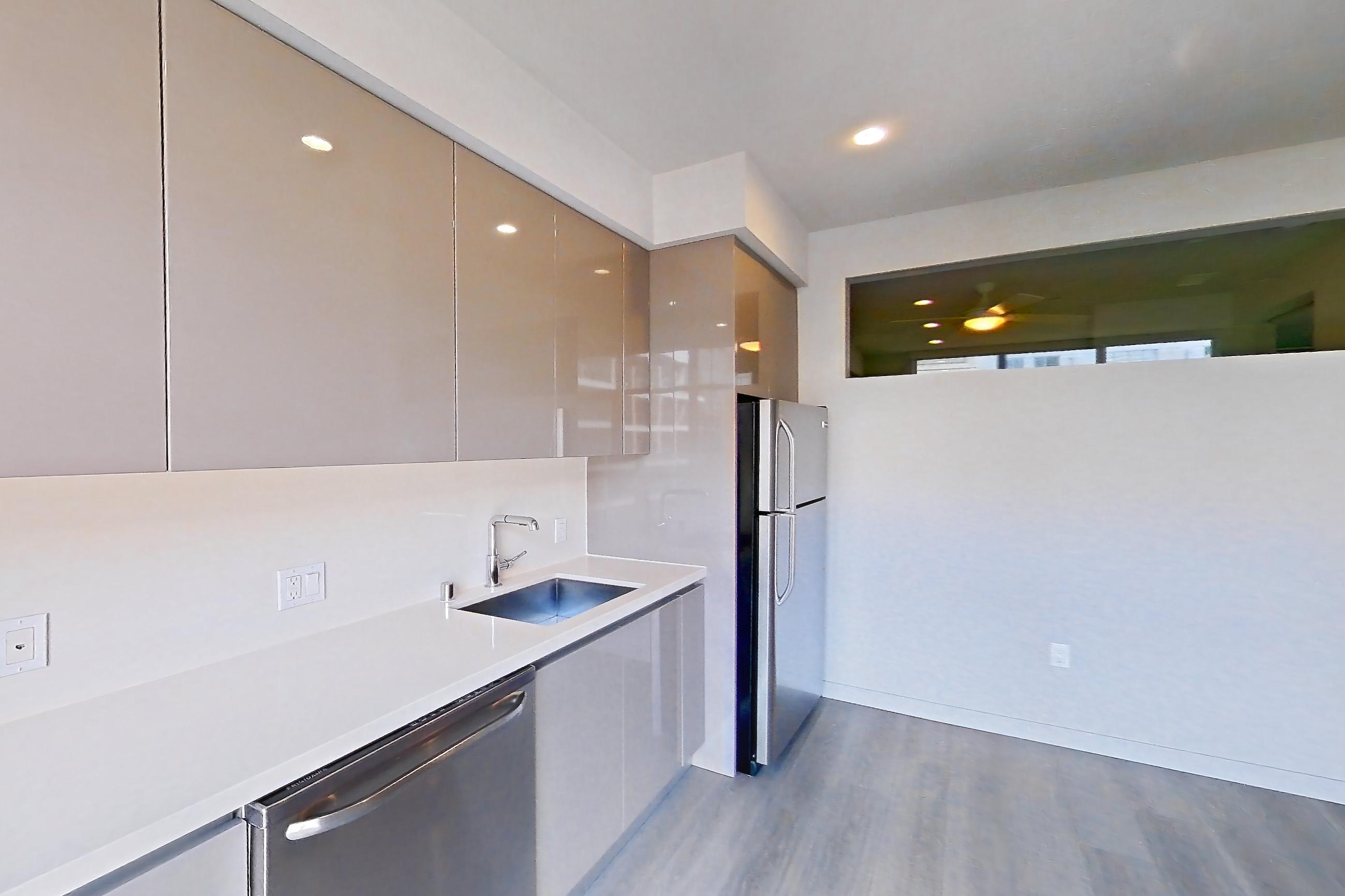 Kitchen with electric range, light countertops, light stone countertops, light wood-finish flooring, oven/range, refrigerator, and stainless steel appliances, Apartment 0-5006 at Eighth and Grand