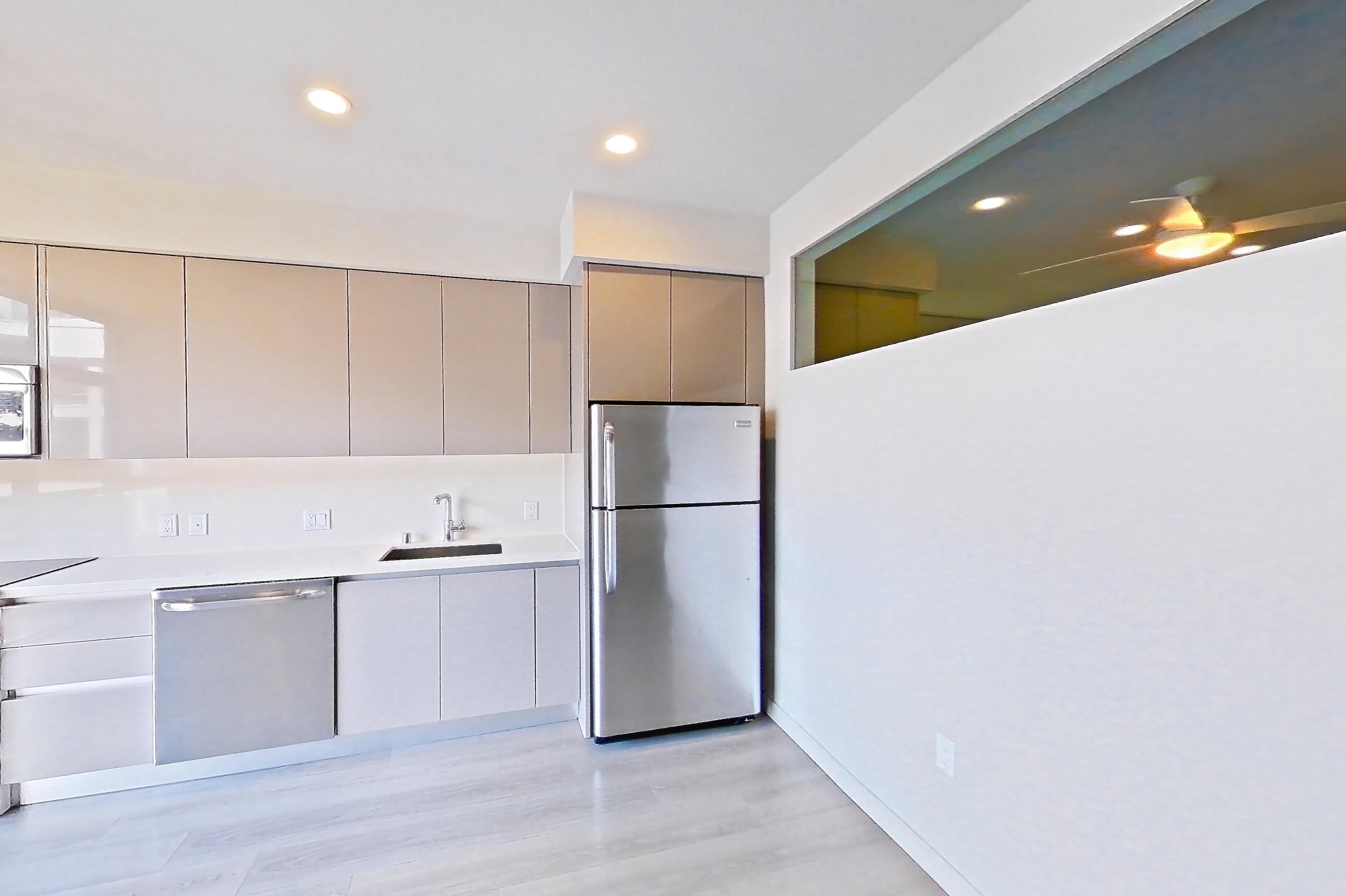 Living room with light countertops, light wood-finish flooring, refrigerator, and stainless steel appliances, Apartment 0-5006 at Eighth and Grand