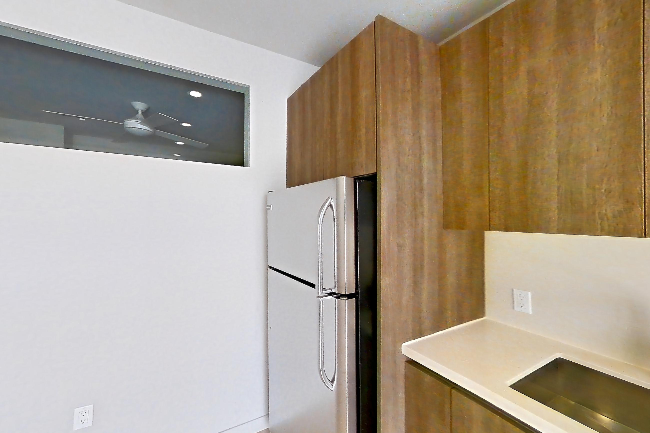 Kitchen with light countertops, light wood-finish flooring, refrigerator, and stainless steel appliances, Apartment 0-5046 at Eighth and Grand