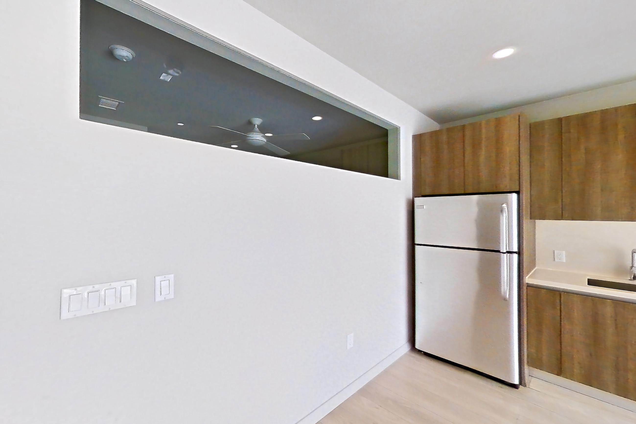 Living room with dishwasher, light countertops, light wood-finish flooring, refrigerator, and stainless steel appliances, Apartment 0-5046 at Eighth and Grand
